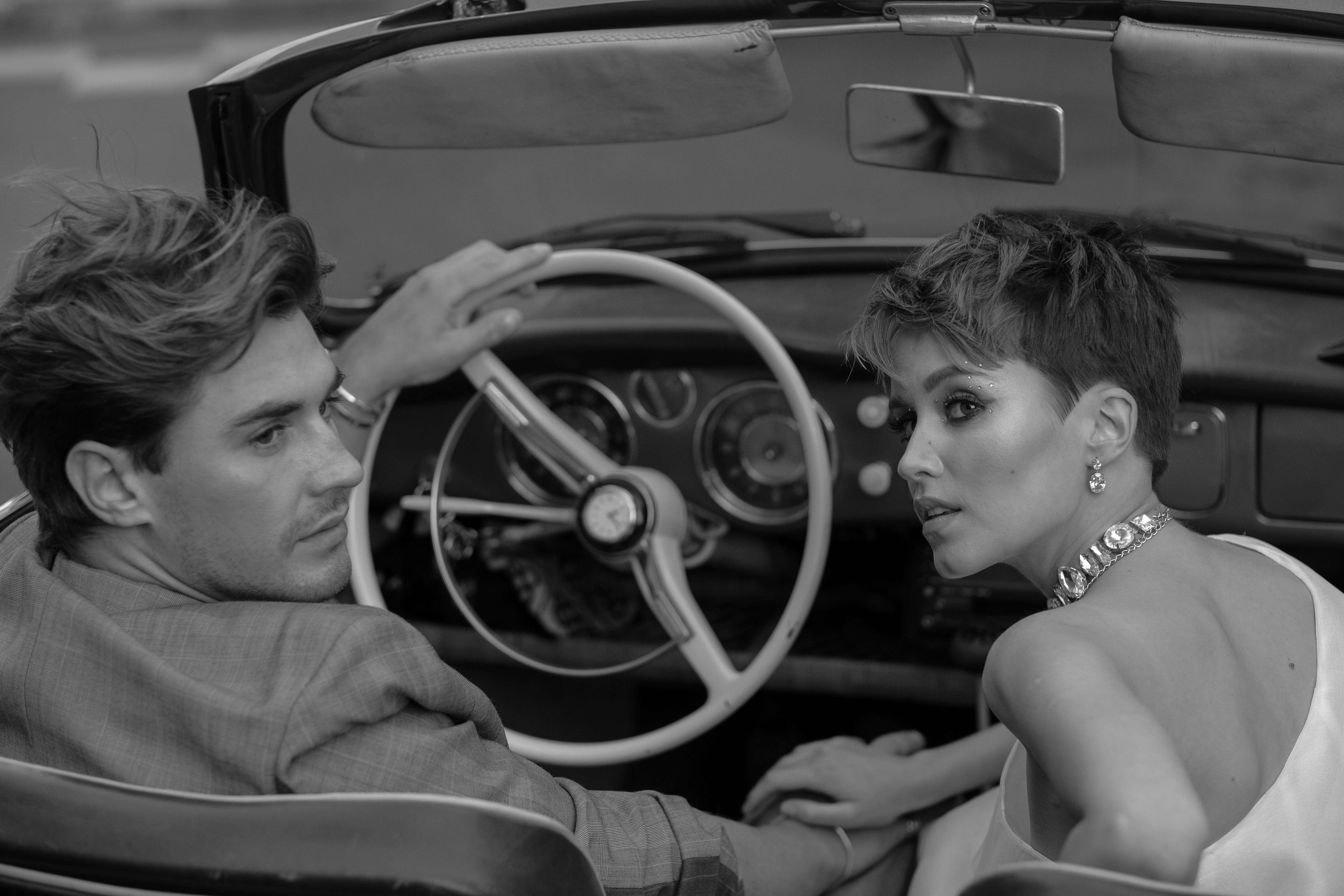 Elegant couple in a vintage convertible, exuding timeless style and sophistication.