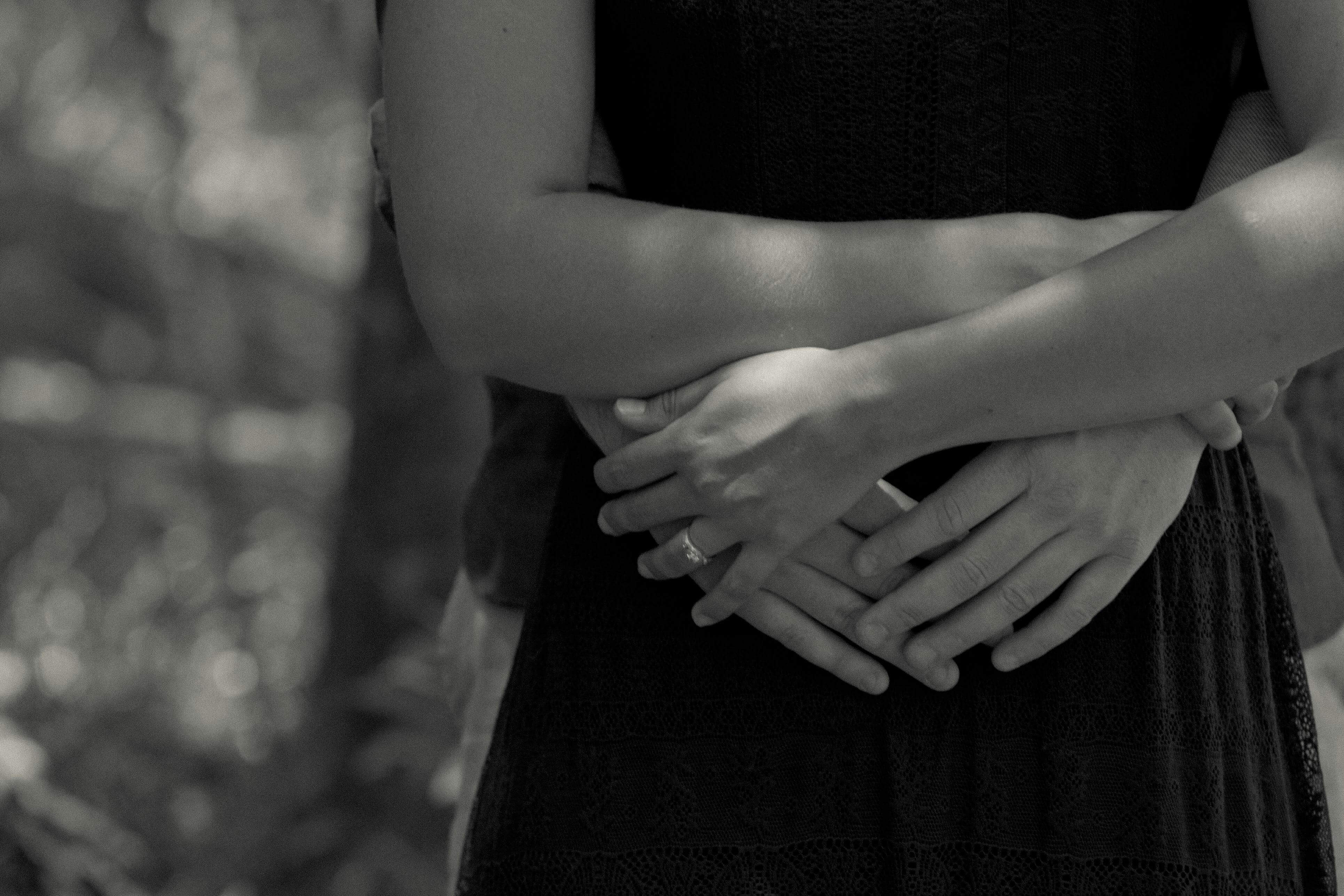 Close-up black and white photo of a couple hugging outdoors, capturing intimacy and love.