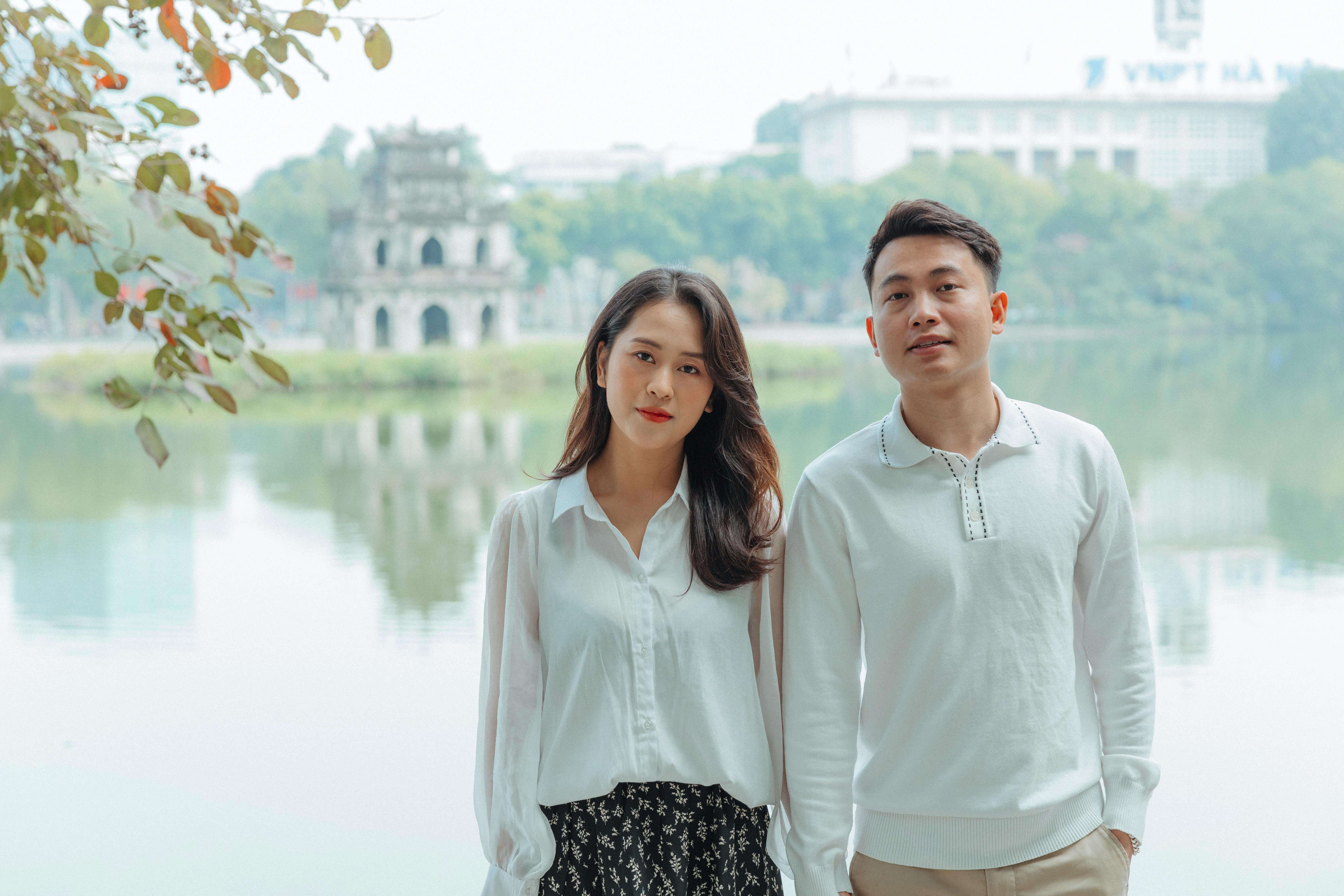 Asian couple enjoying a romantic moment near Hoan Kiem Lake, embracing love and nature.
