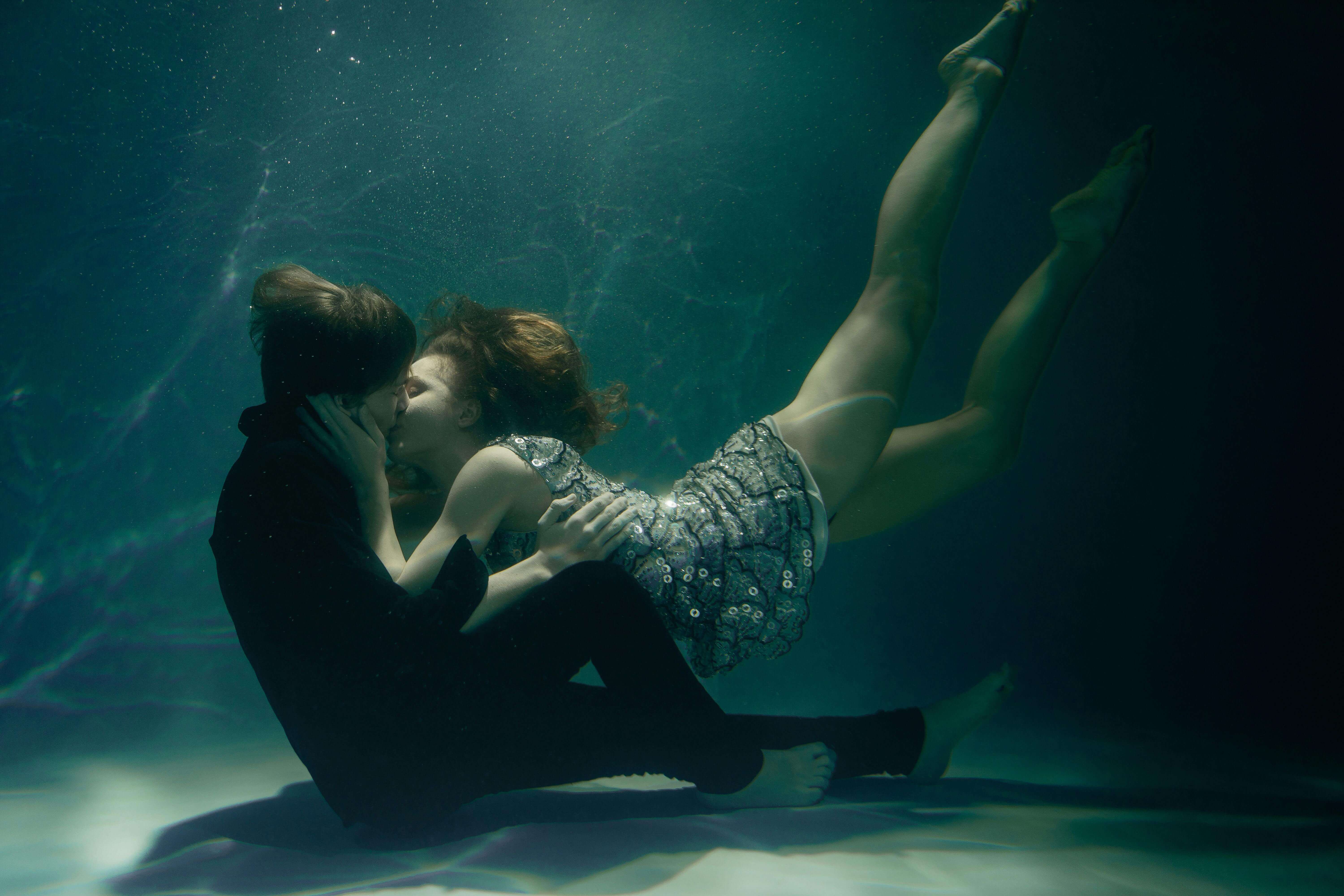Couple embracing and kissing underwater in an artistic scene.