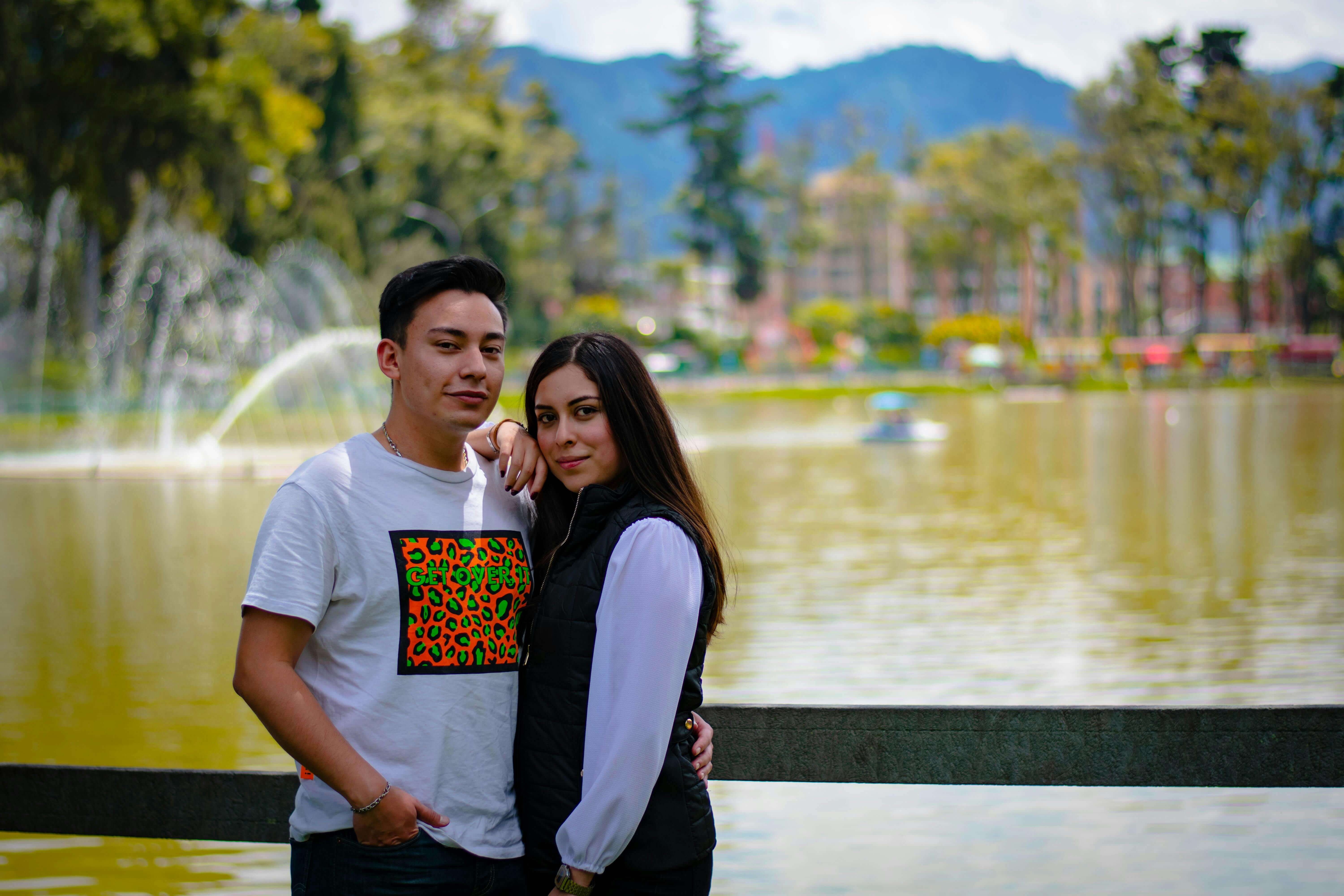 A couple enjoying a serene moment by a lake during a sunny day.