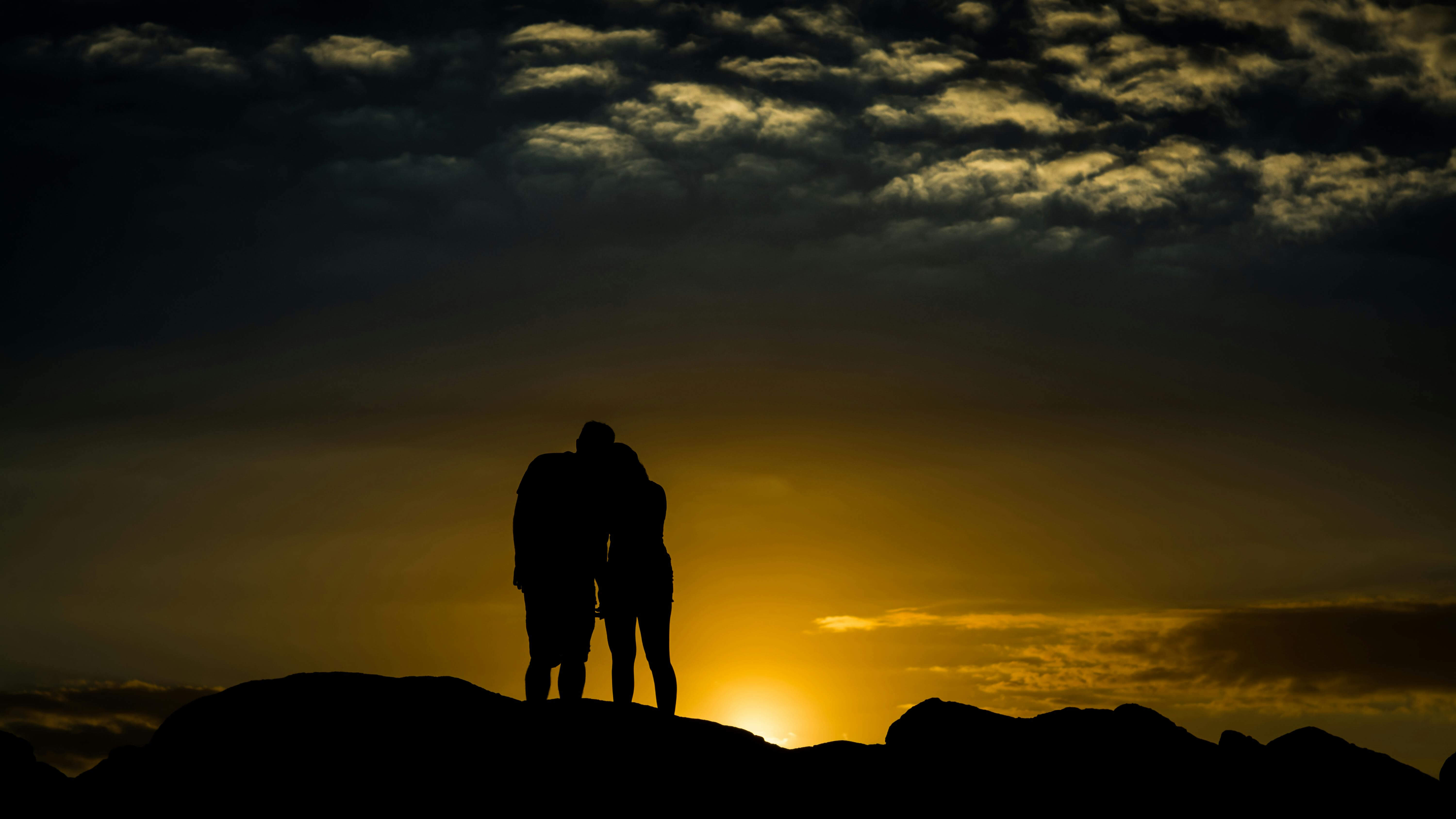 Silhouetted couple embracing at sunset, creating a romantic and serene atmosphere.