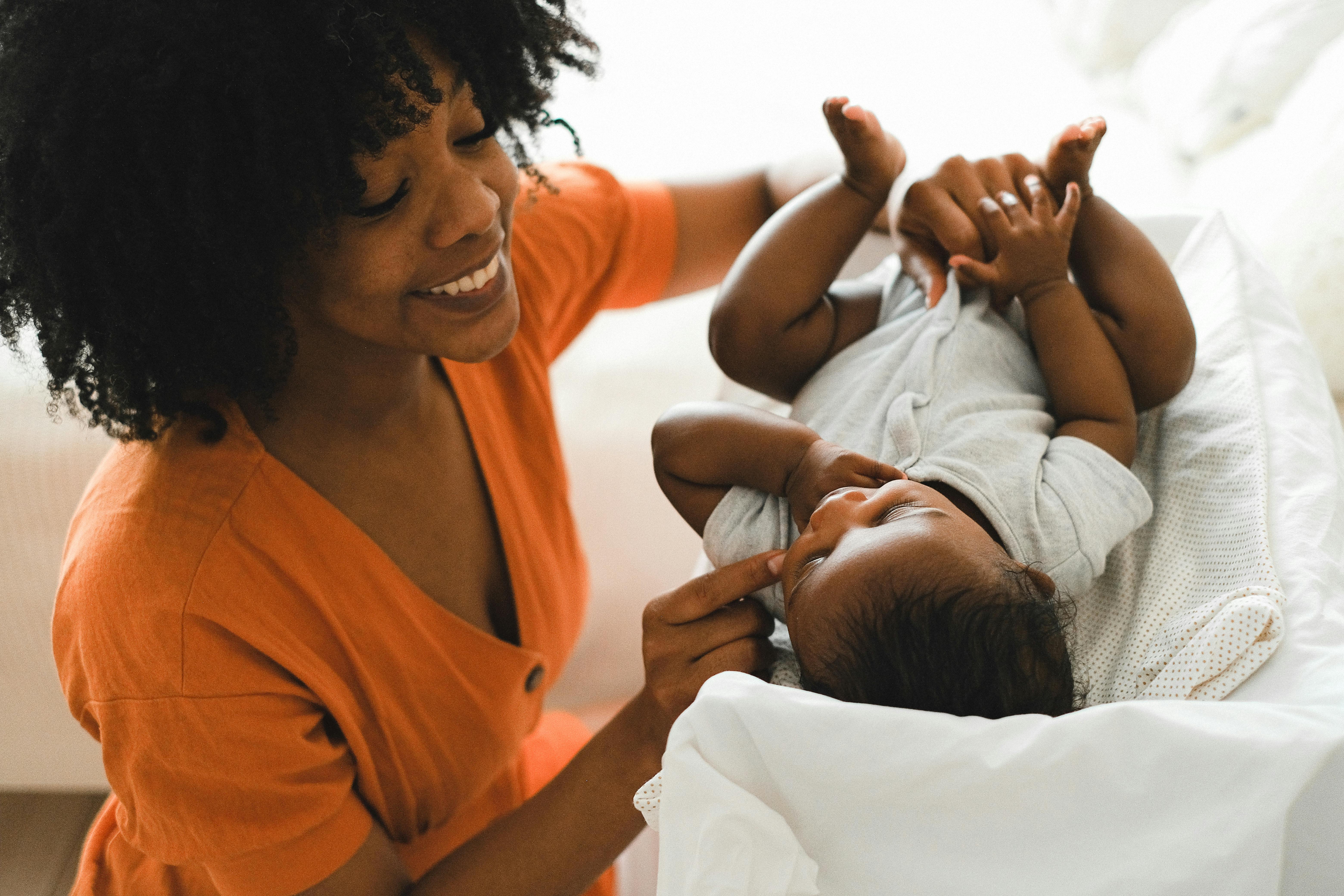 A loving mother playfully engages with her baby on a bed, showing warmth and happiness.