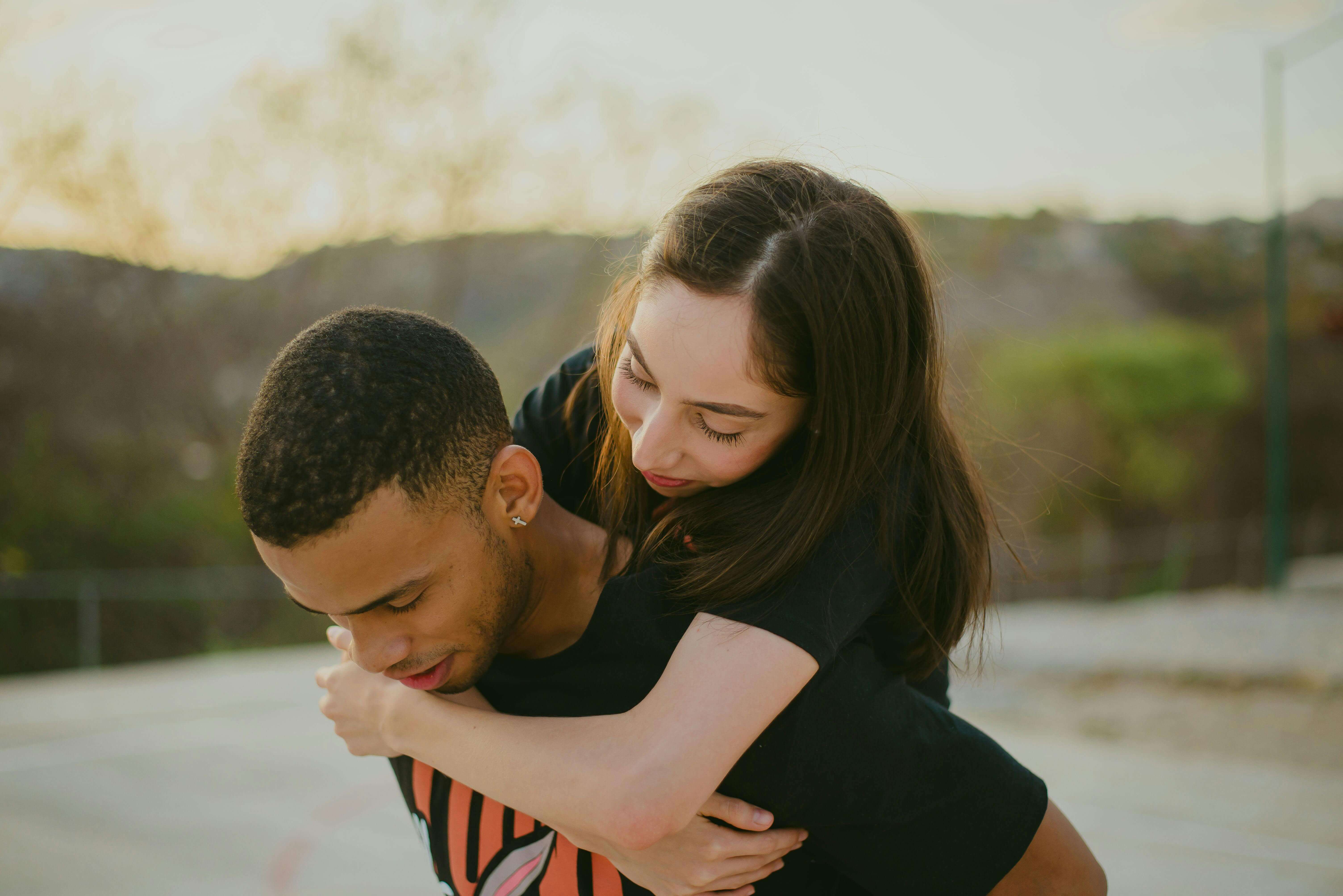 Young couple joyfully embracing outdoors on a sunny day, symbolizing love and togetherness.