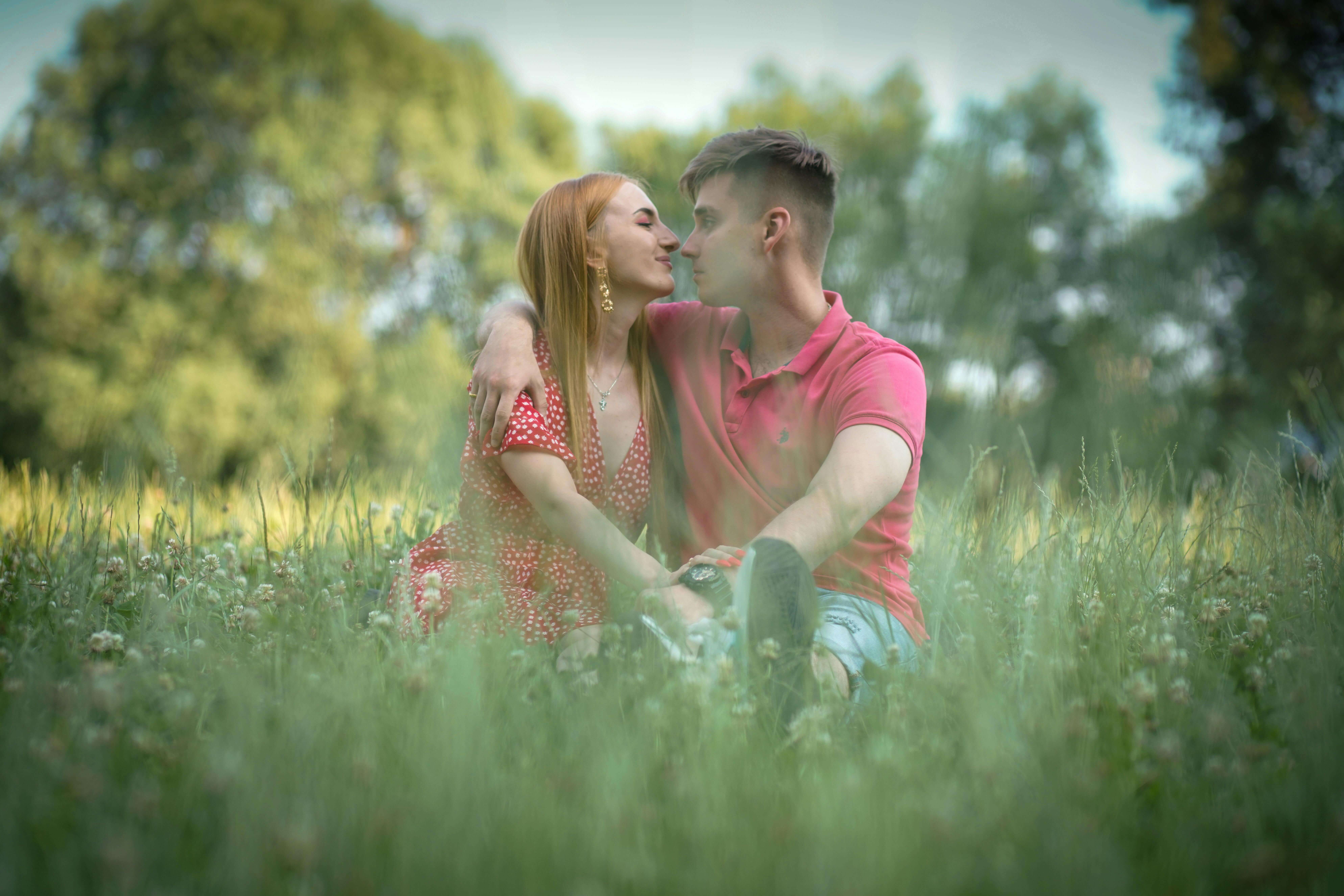 A loving couple embraces in a sunlit meadow surrounded by lush greenery.