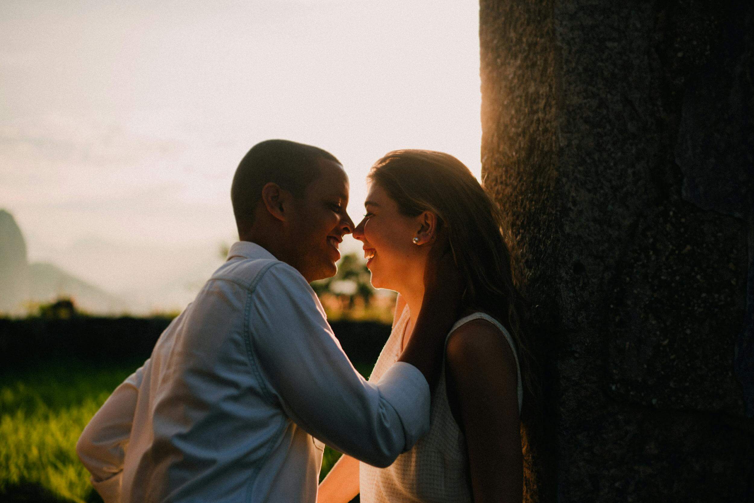 A couple embraces warmly at sunset near Jurujuba, Brazil, capturing a moment of love and happiness.