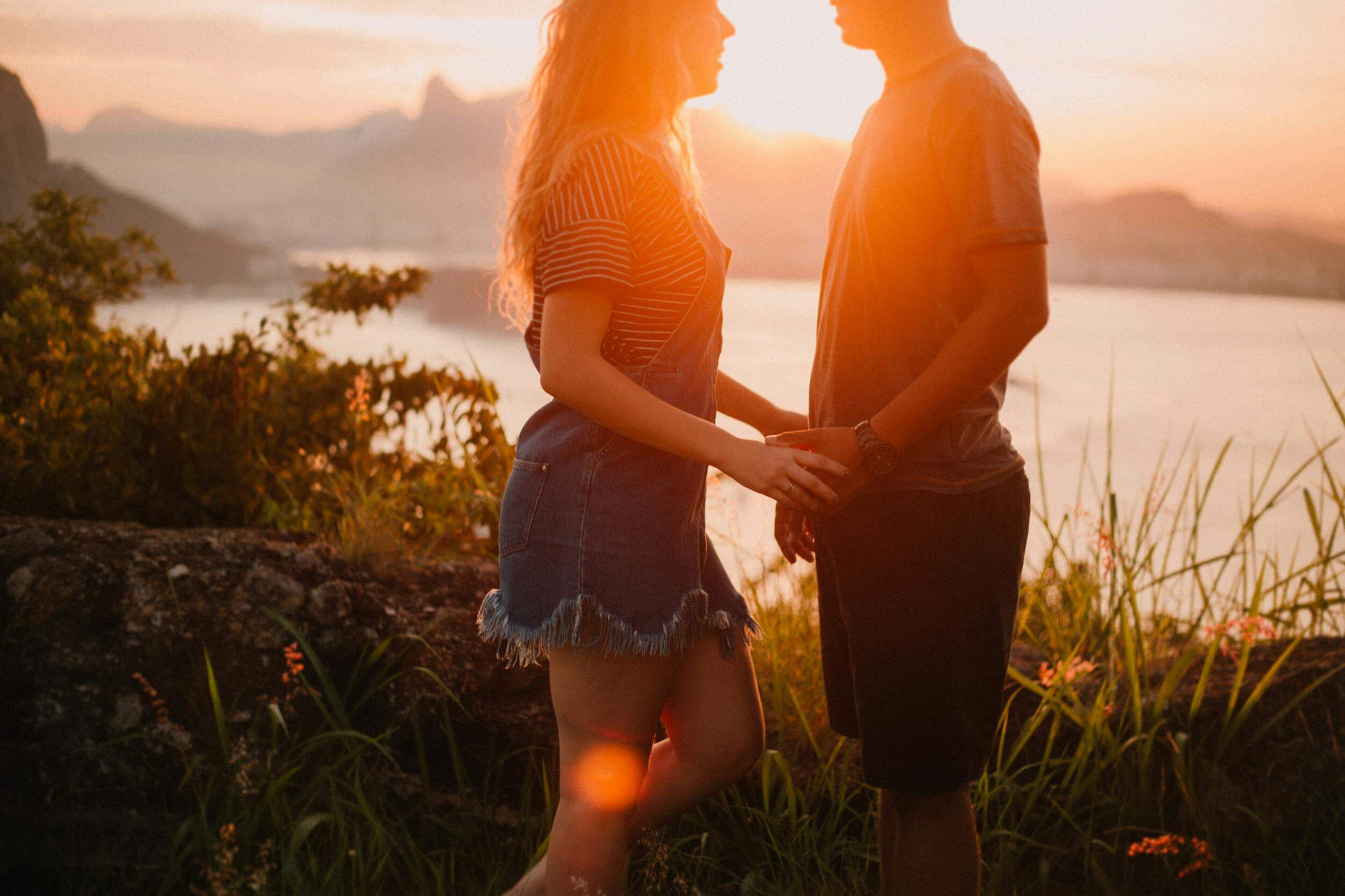 A couple enjoys a romantic sunset overlooking Rio's skyline in Jurujuba, Brazil.