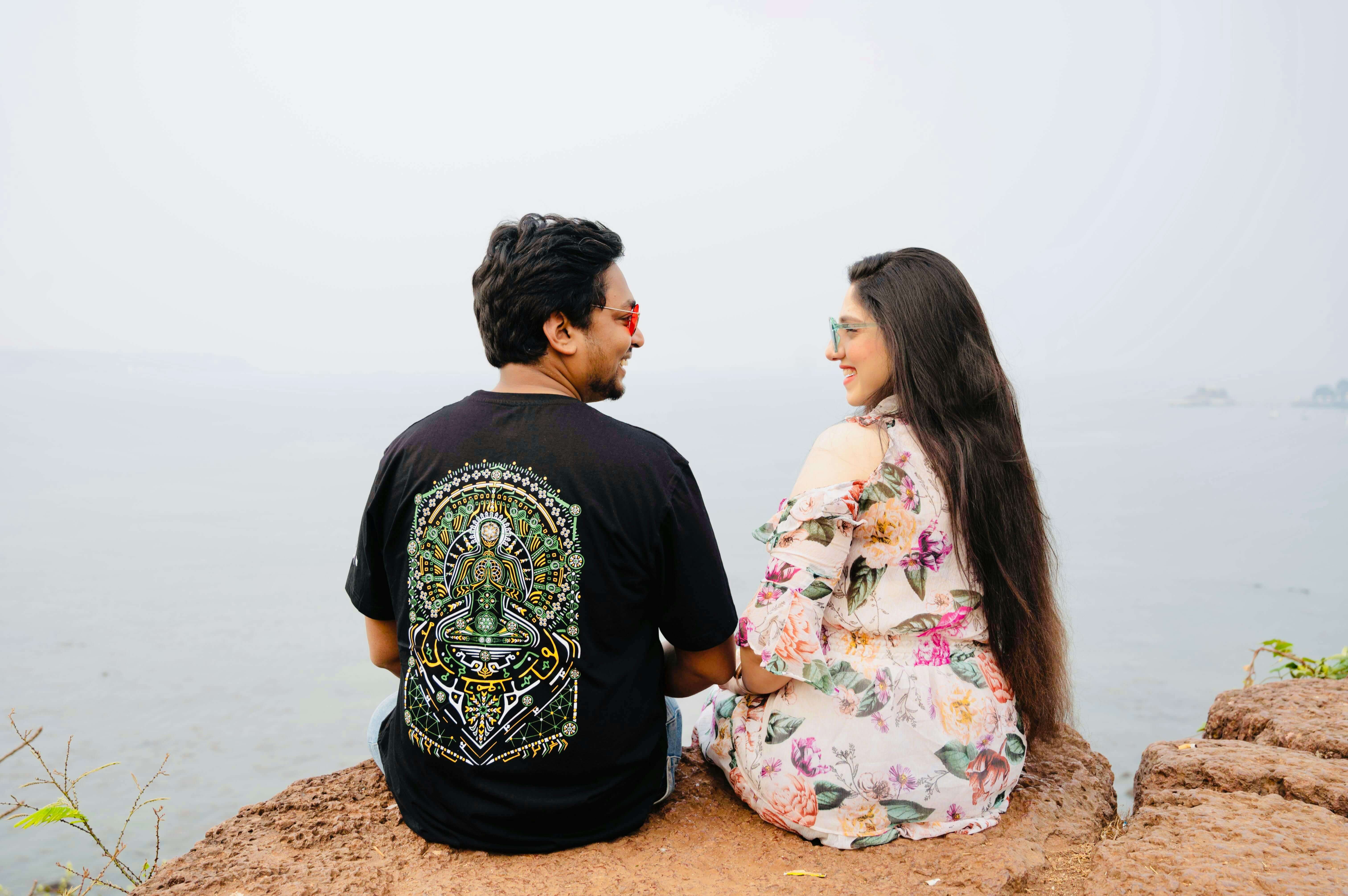 Couple sitting on a cliff edge, enjoying a peaceful seaside view and each other's company.