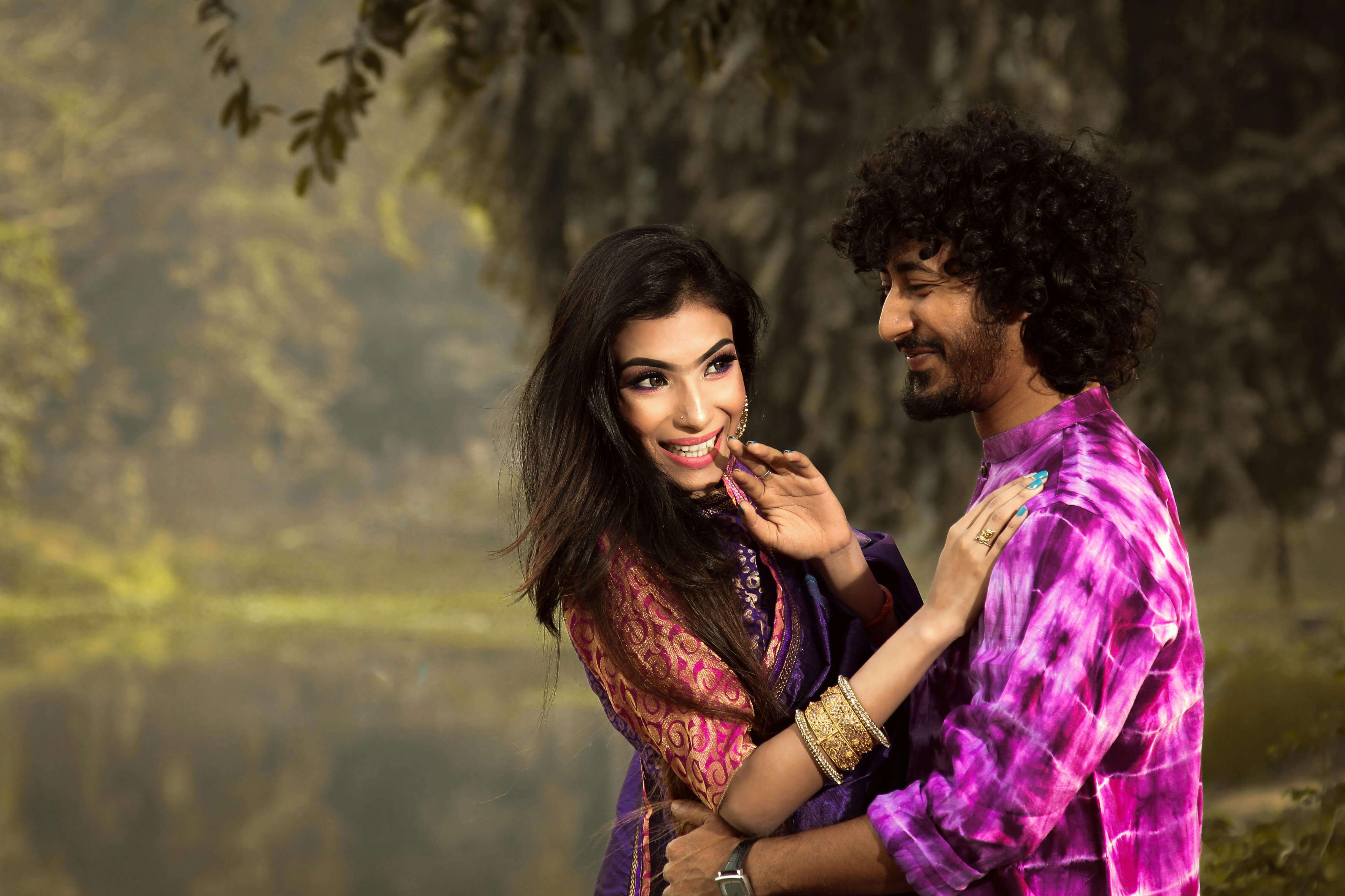 Couple embracing and smiling by a tranquil river, exuding happiness and romance.