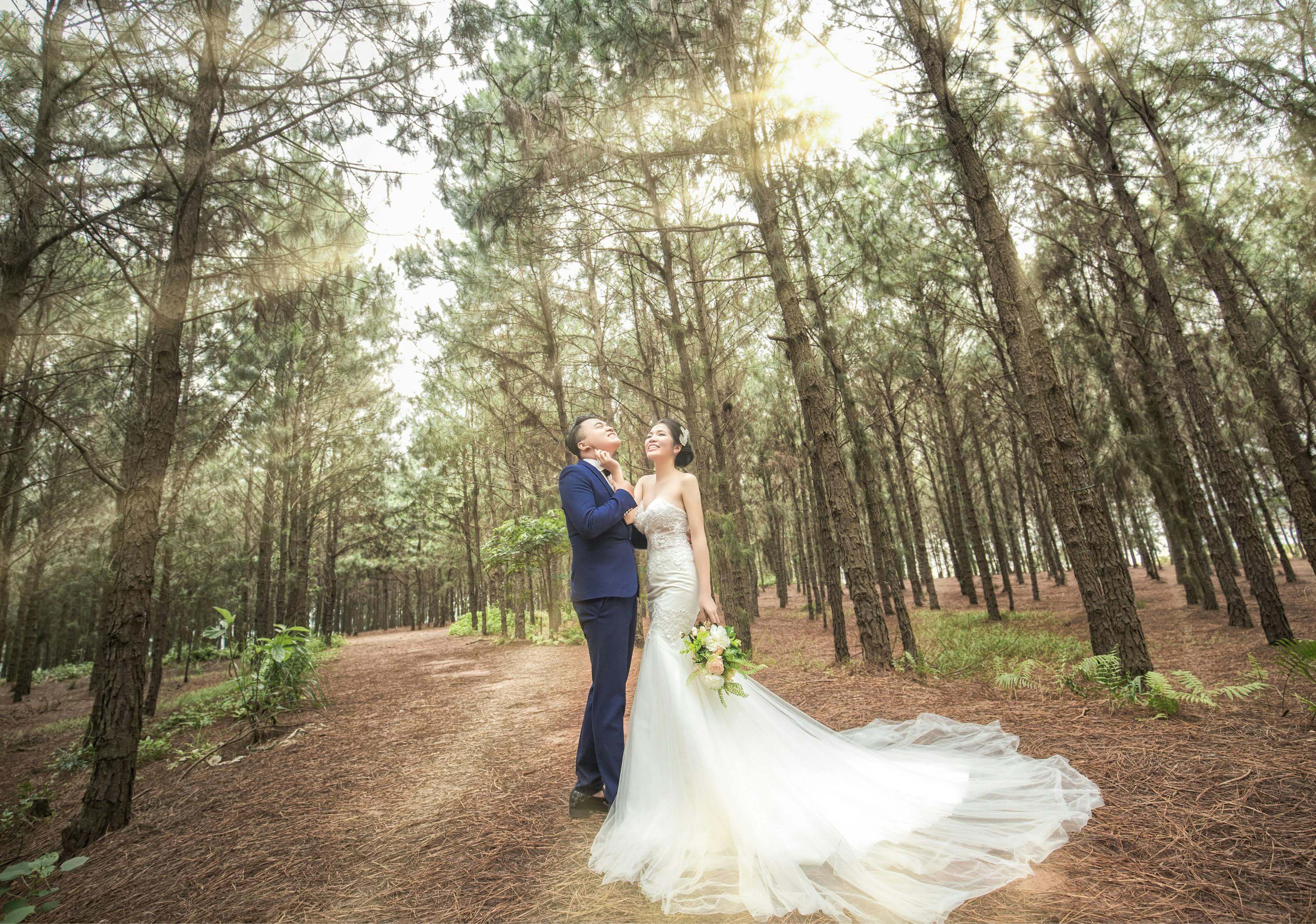 Bride and groom celebrating their wedding in a sunlit forest, radiating love and romance.