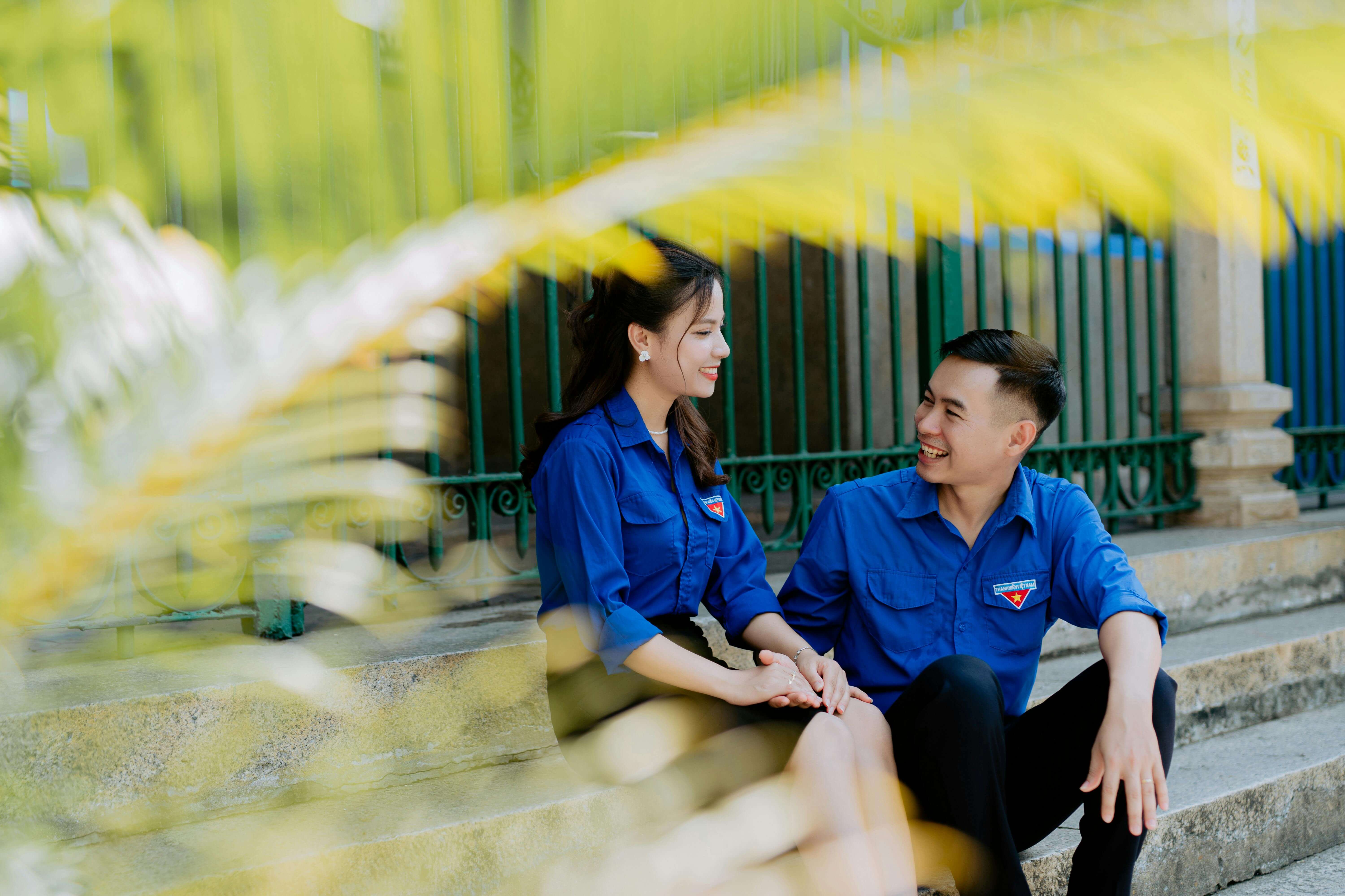 A young couple in matching blue shirts enjoys a loving moment together outdoors.