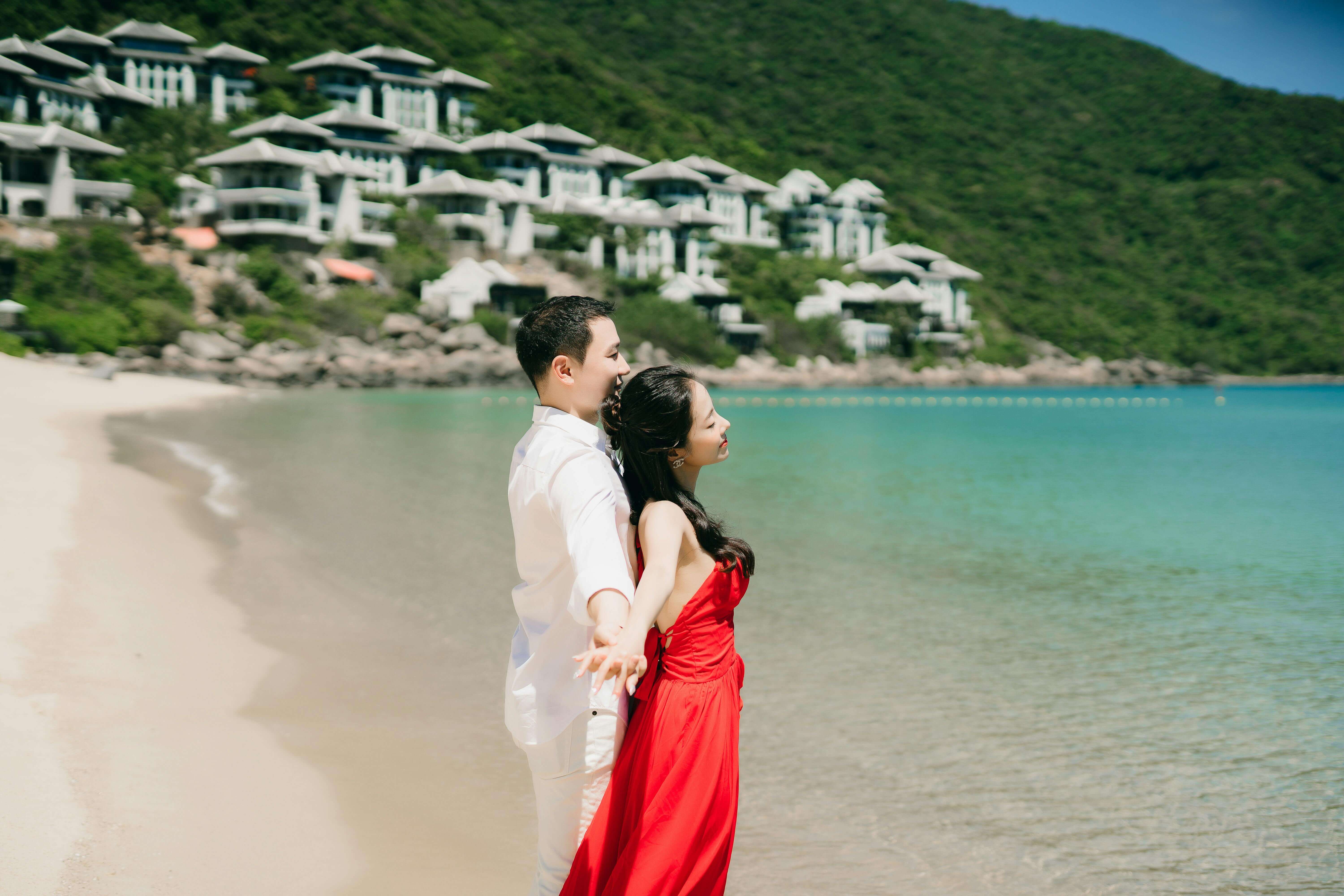A couple in love embracing on a picturesque beach with scenic resort views, perfect for romantic getaways.