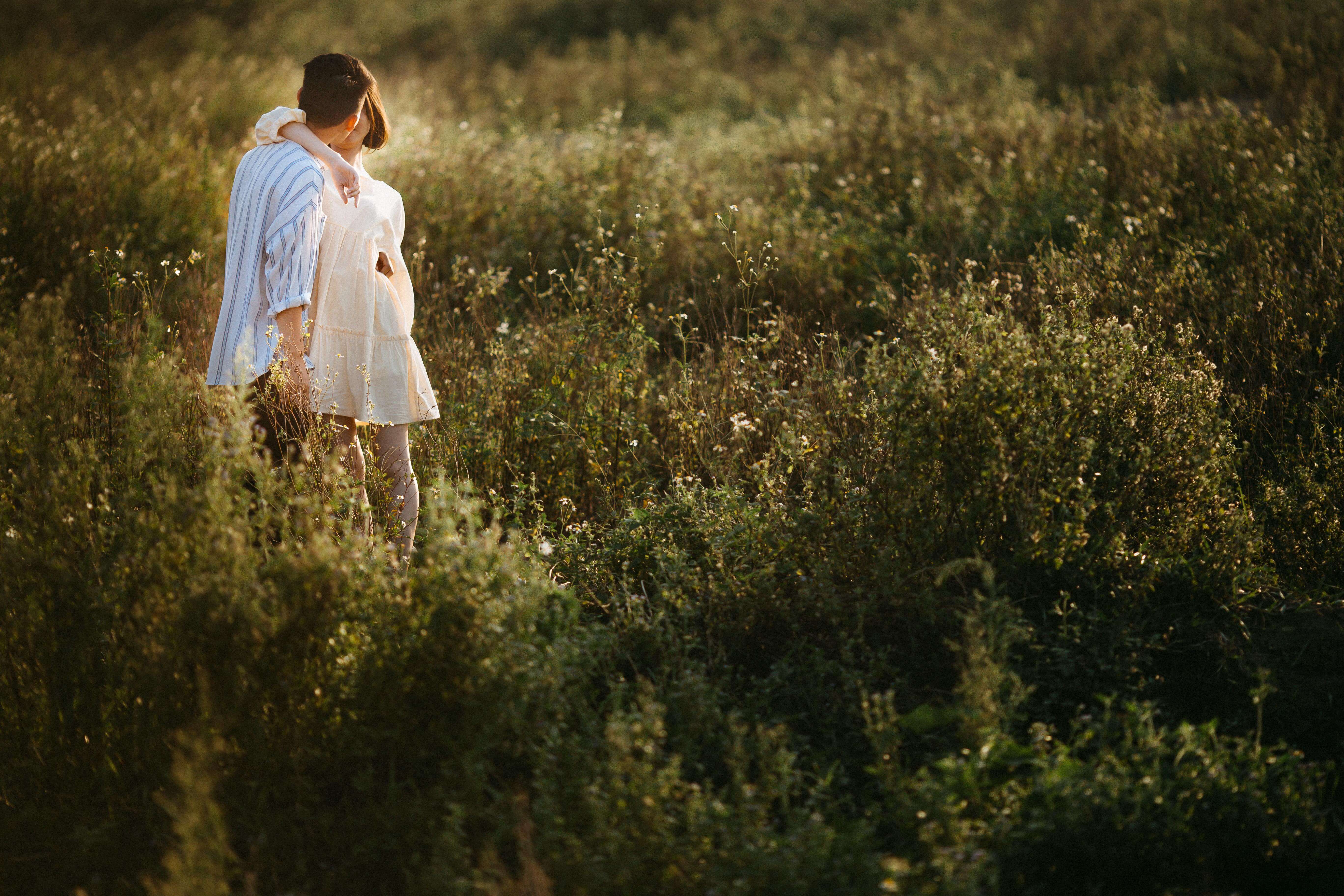 A couple embraces in a lush field in Vietnam, capturing a serene moment at sunset.