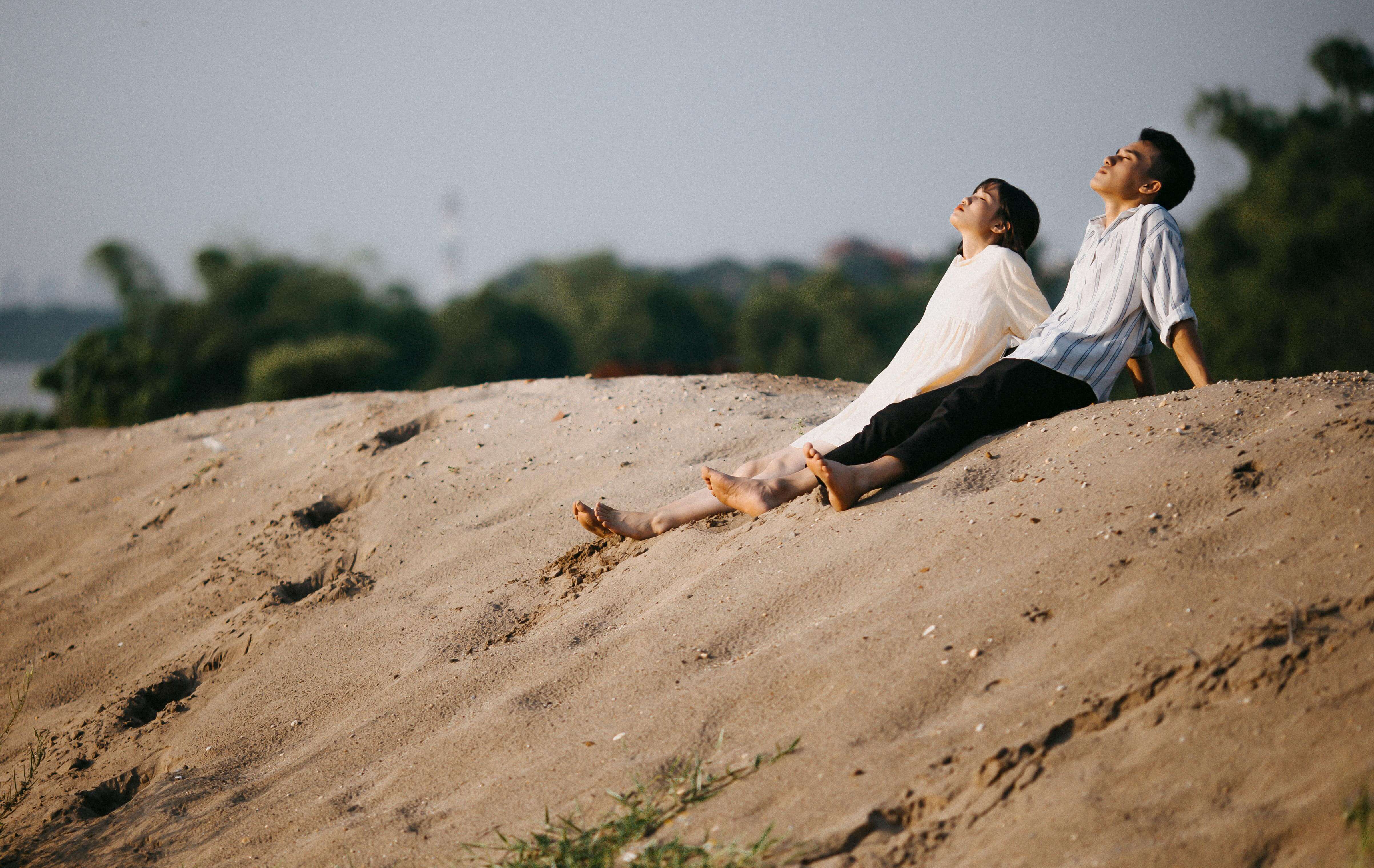 A couple enjoying a peaceful moment on sandy dunes, embracing nature and leisure.