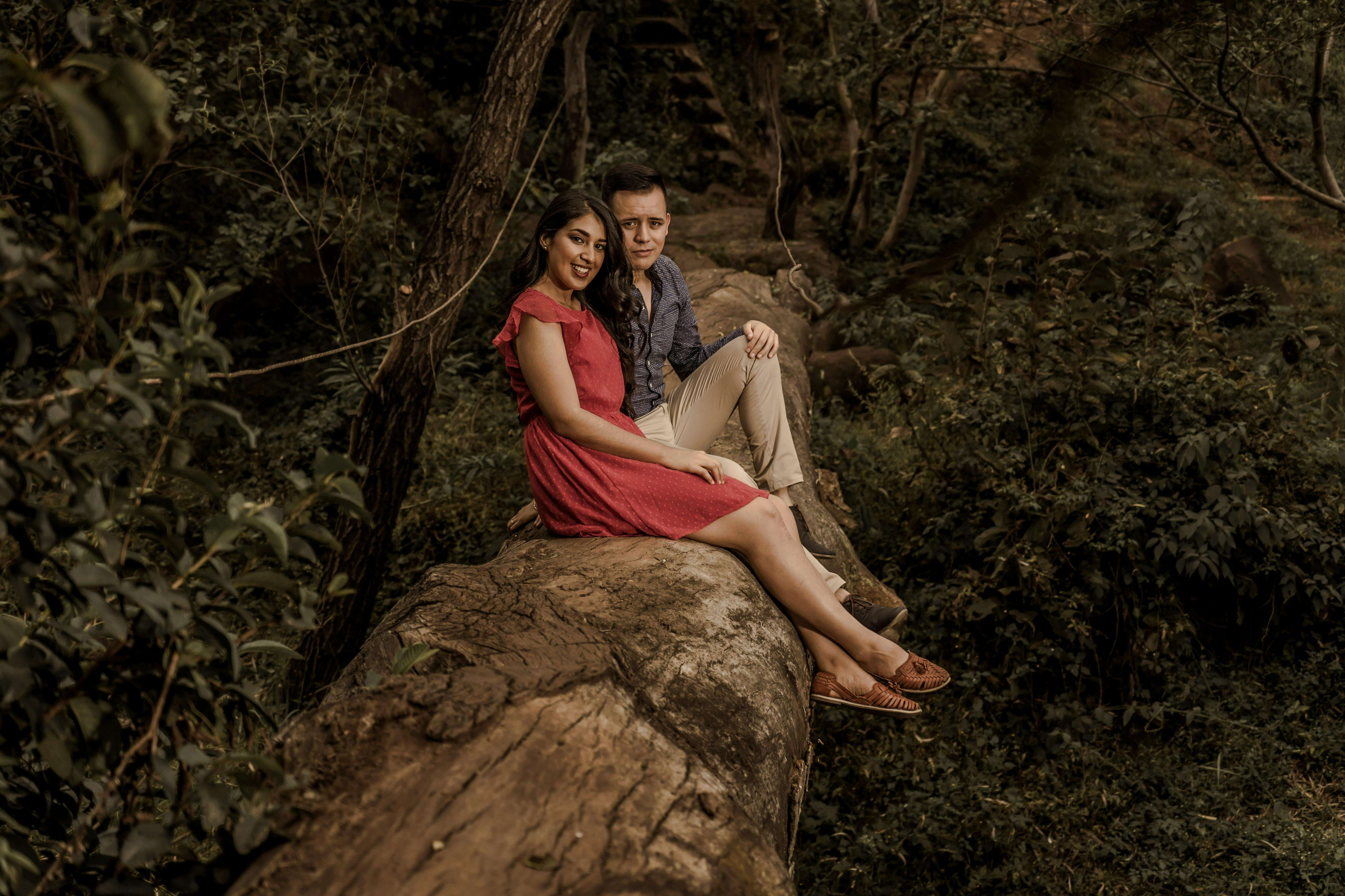 A loving couple sitting on a log in a serene forest setting, enjoying a peaceful moment.