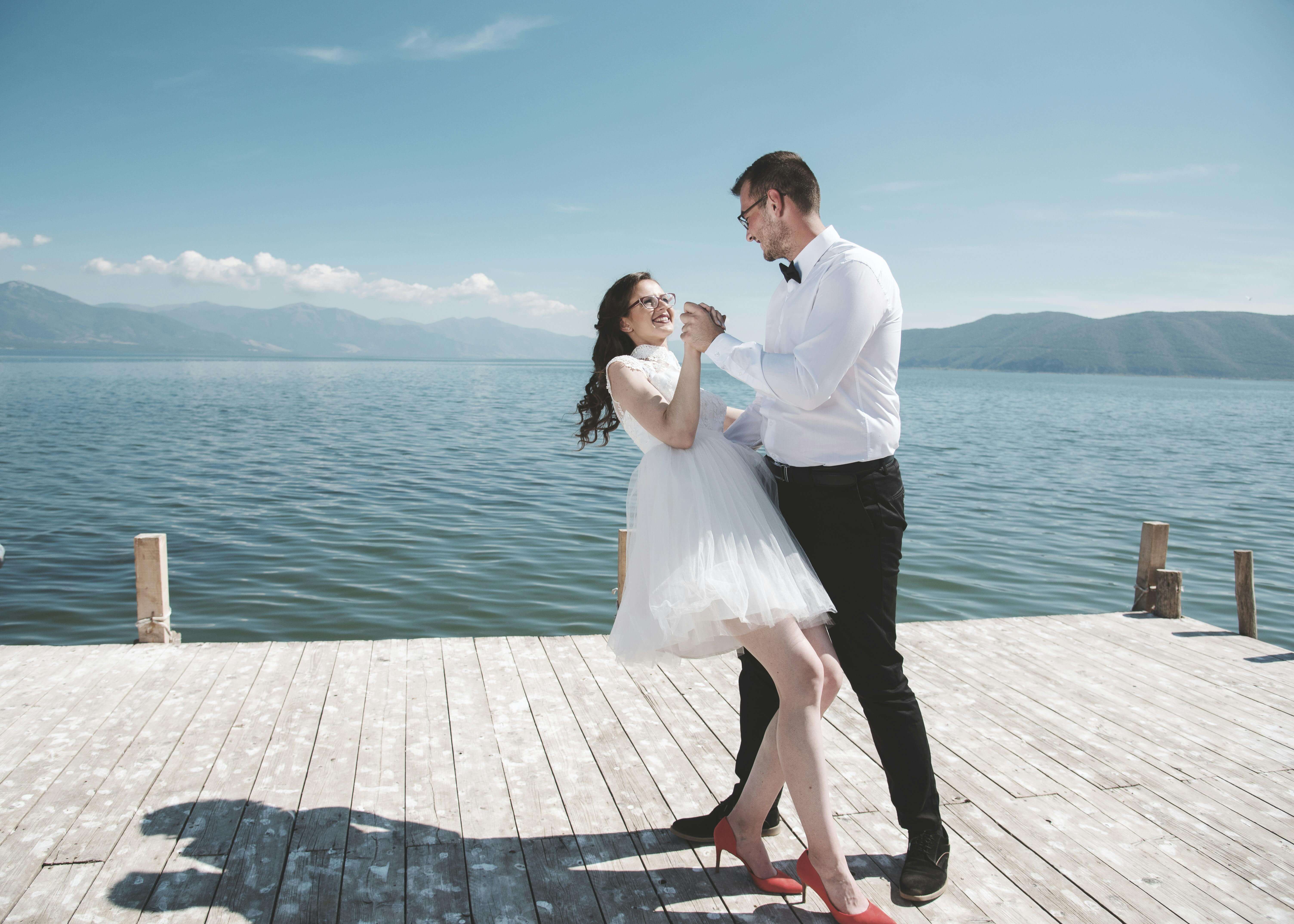 A couple joyfully dances on a dock by Lake Oteshevo, embracing love under a sunny sky.