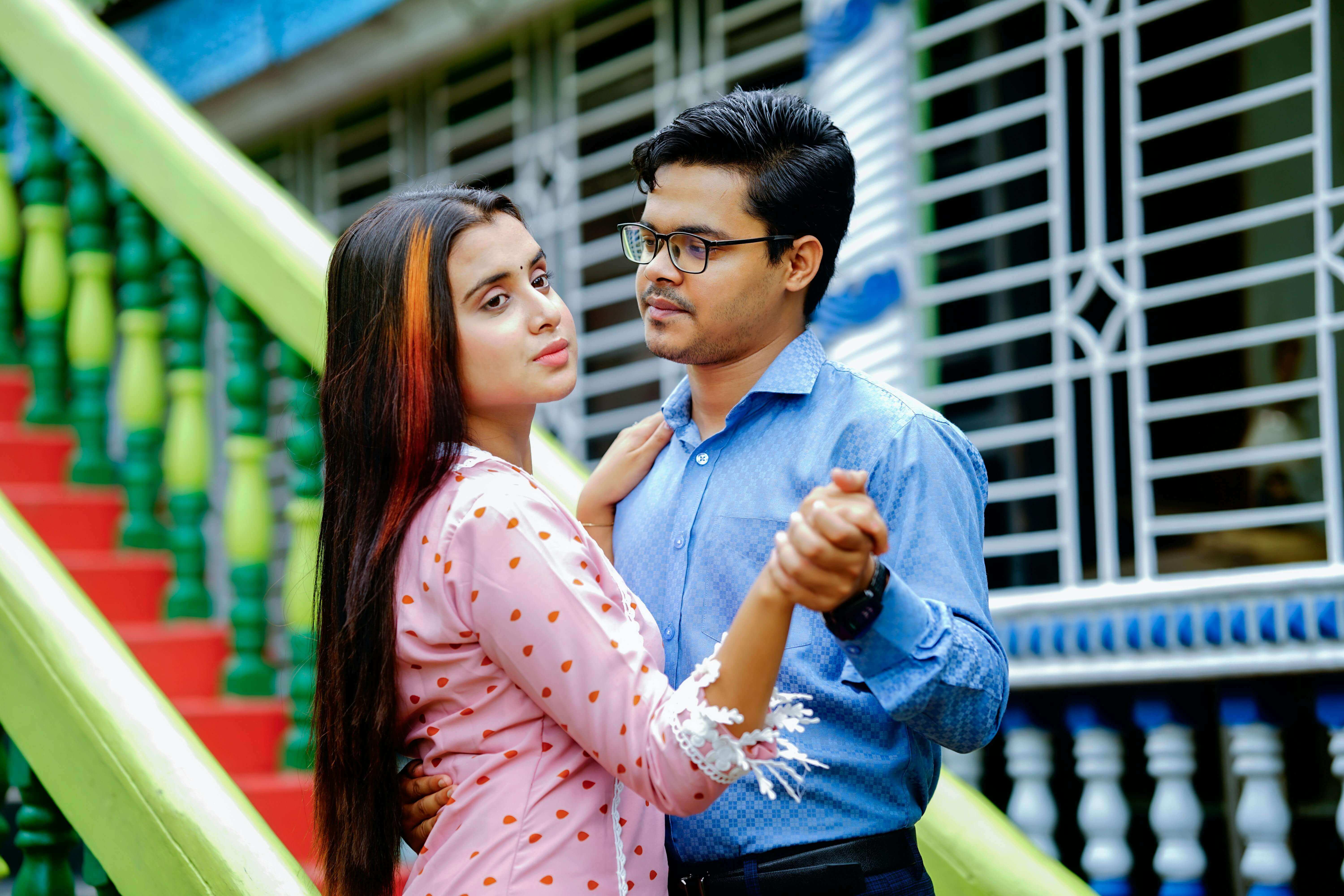 A young couple embracing and dancing outdoors with a colorful background.