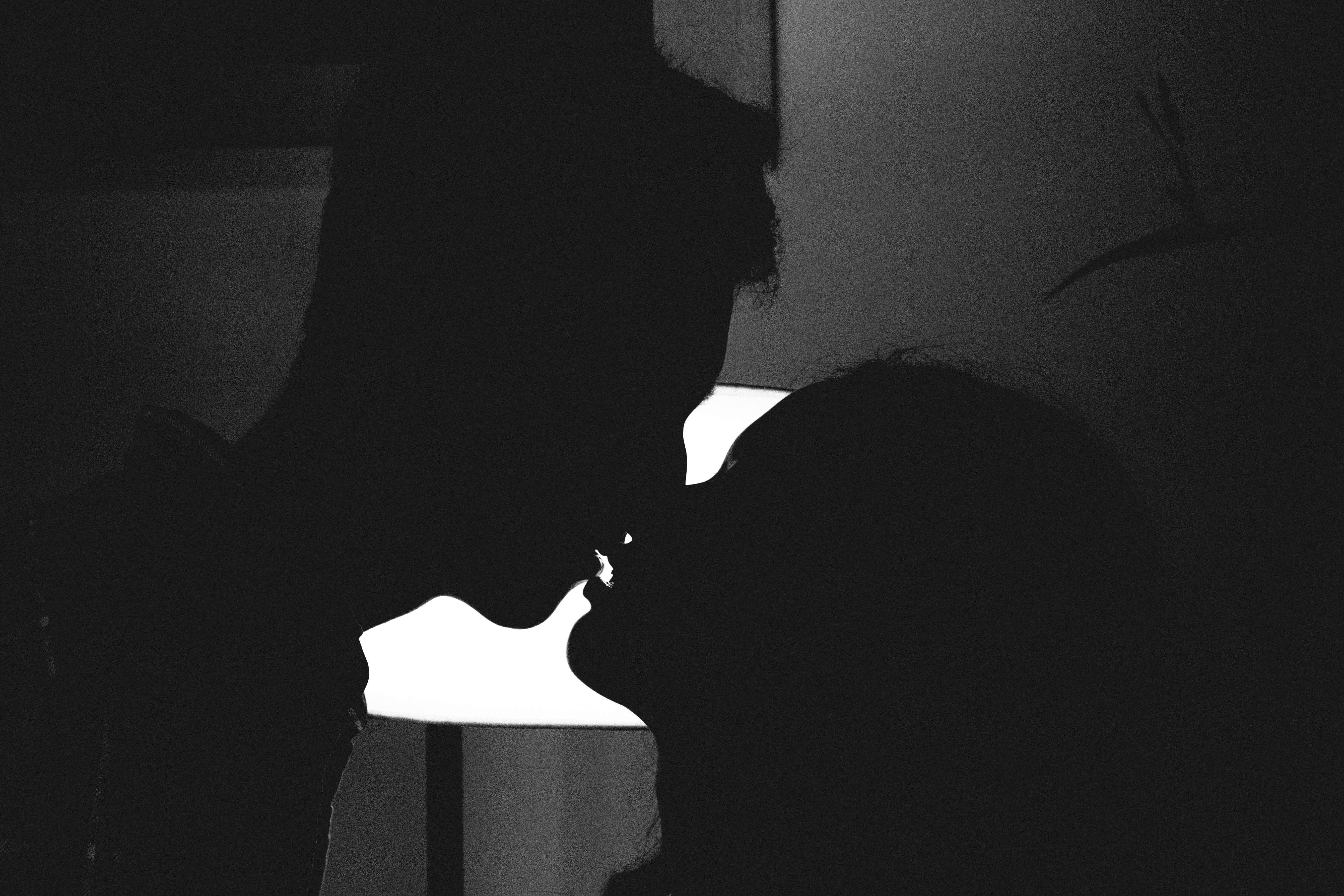 Silhouette of a couple kissing in a romantic and intimate moment against a bright light.