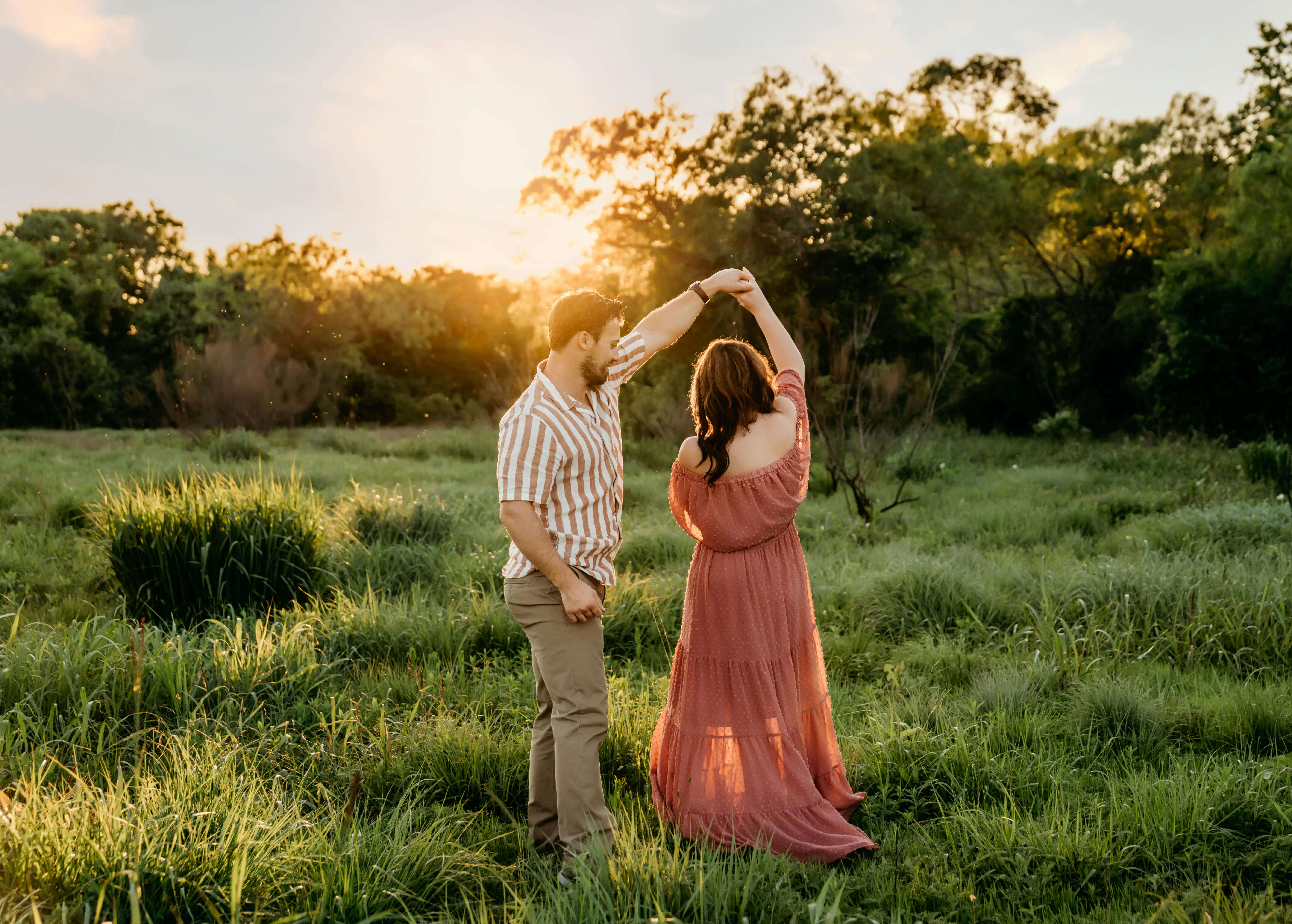 Couple dancing romantically in a lush meadow during a beautiful Austin sunset.
