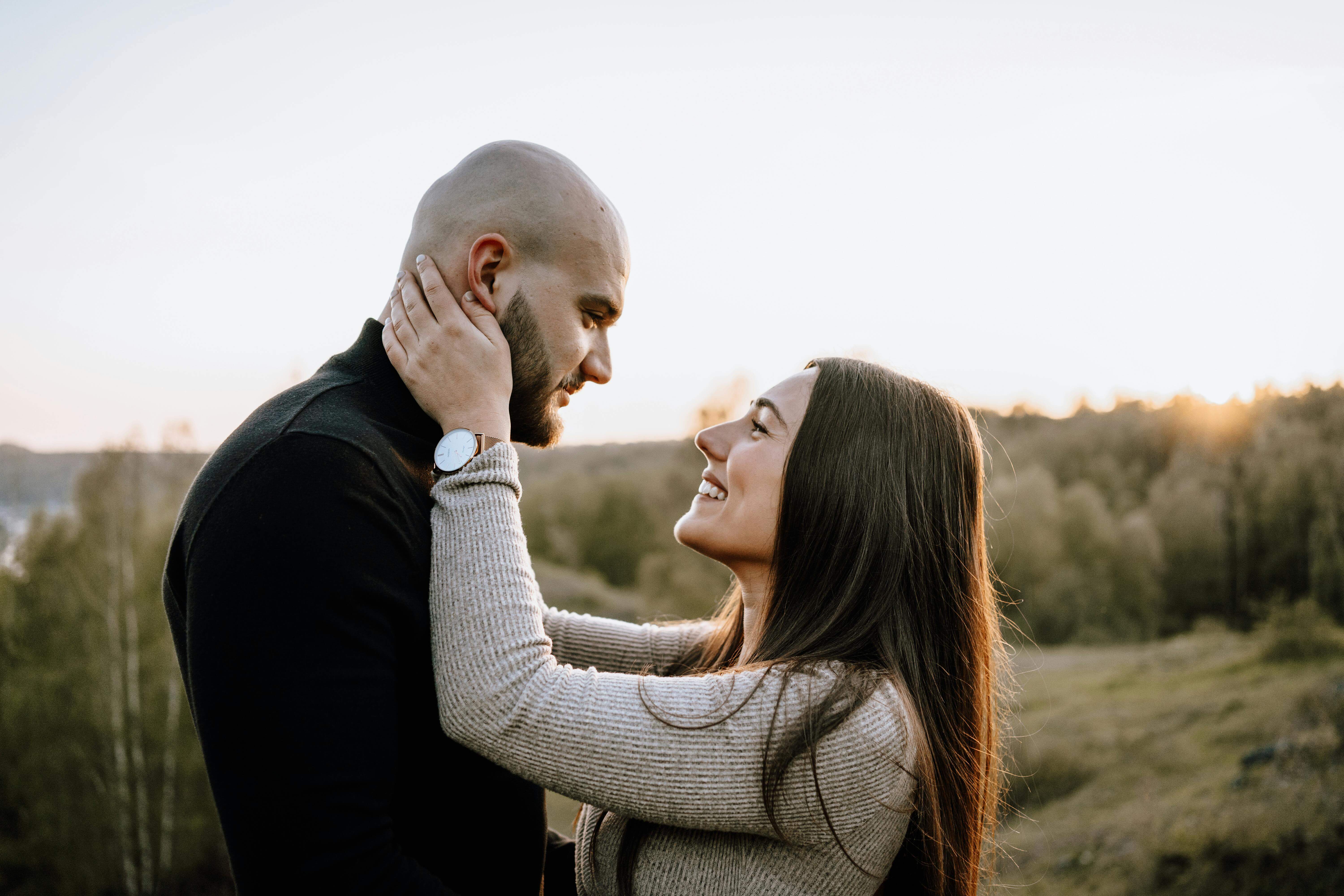 Romantic couple embracing outdoors during sunset, showcasing love and connection.