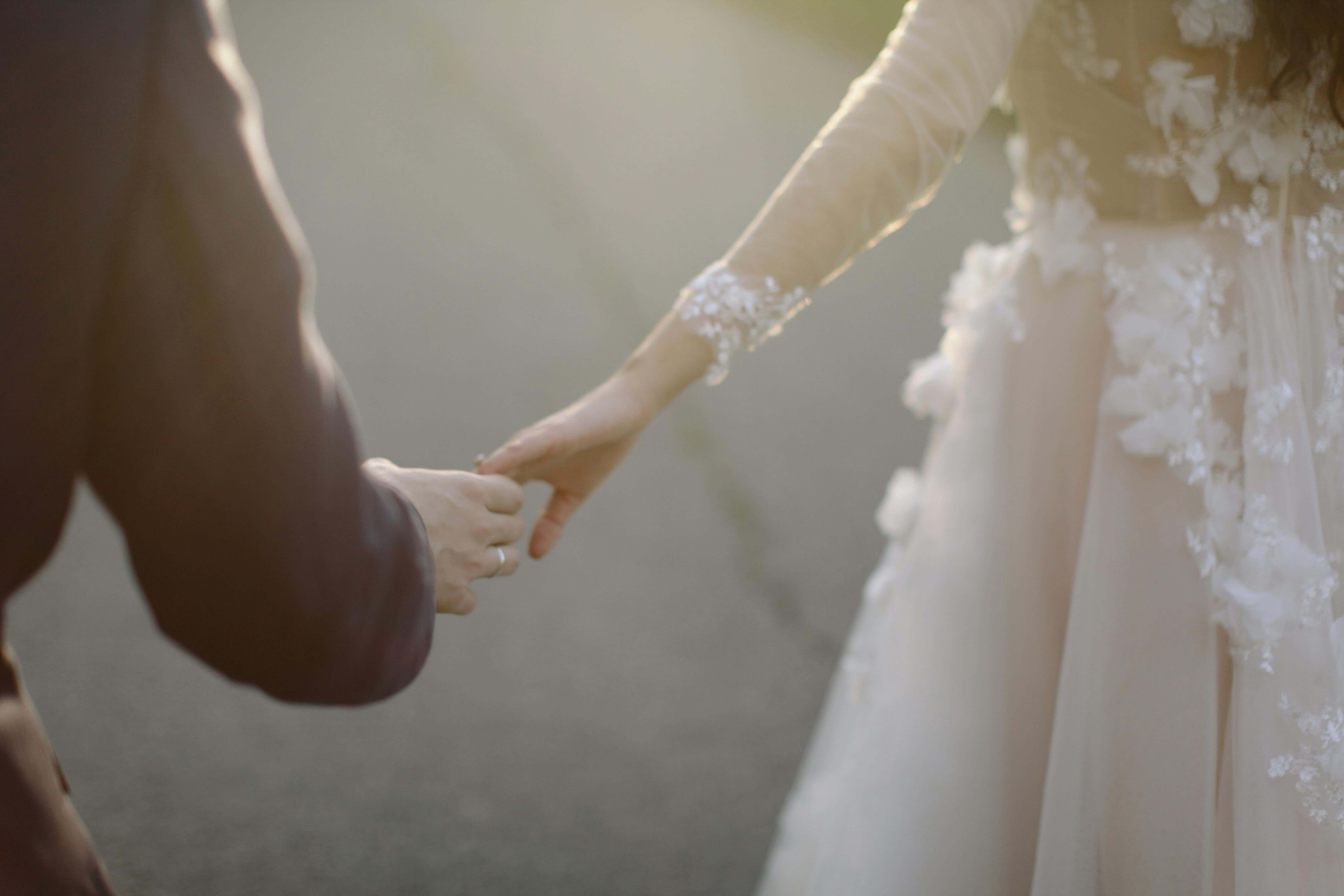 A tender moment captured of a bride and groom holding hands, symbolizing love and togetherness.
