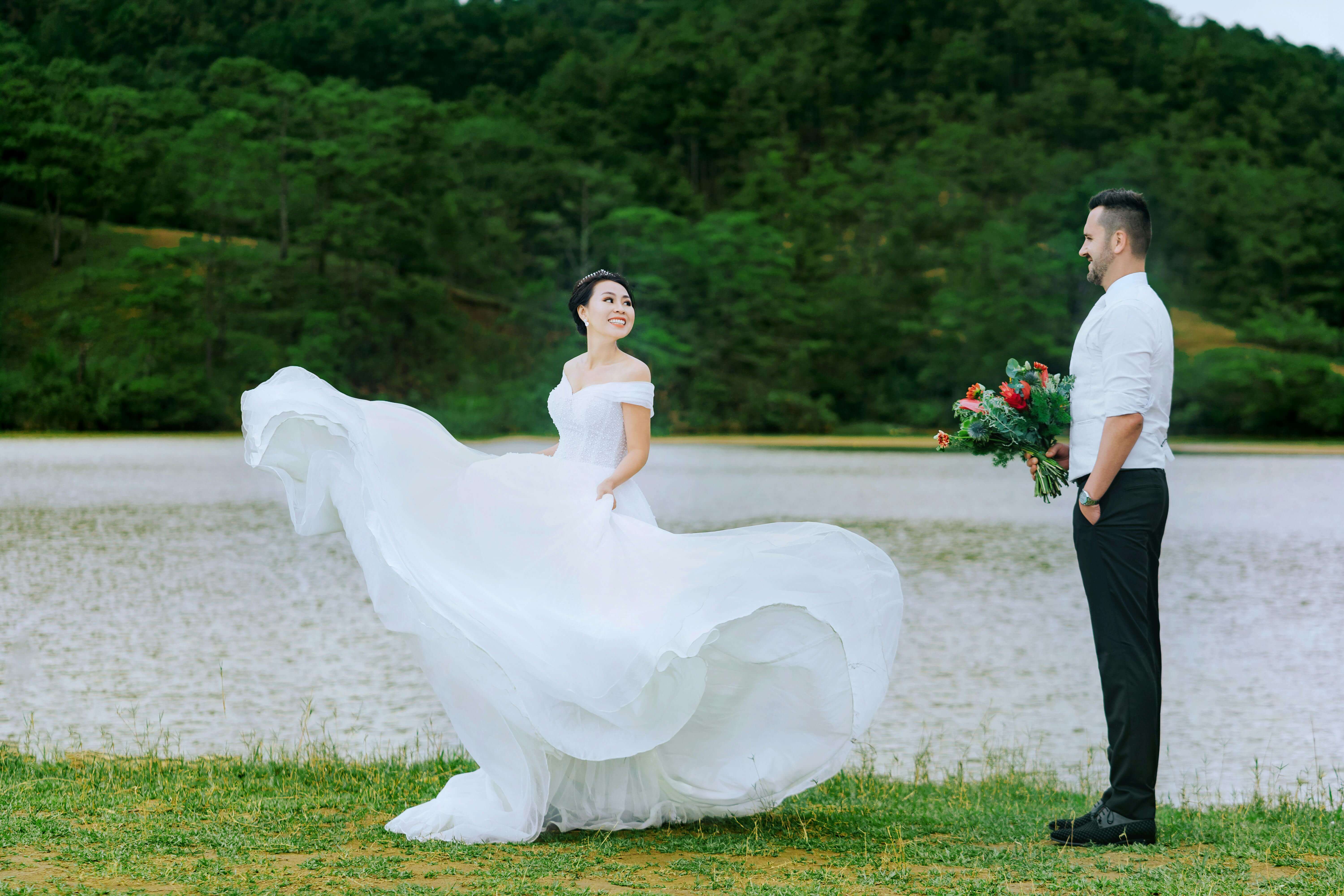 A joyful couple celebrates their wedding day near a scenic lake, capturing love and elegance.