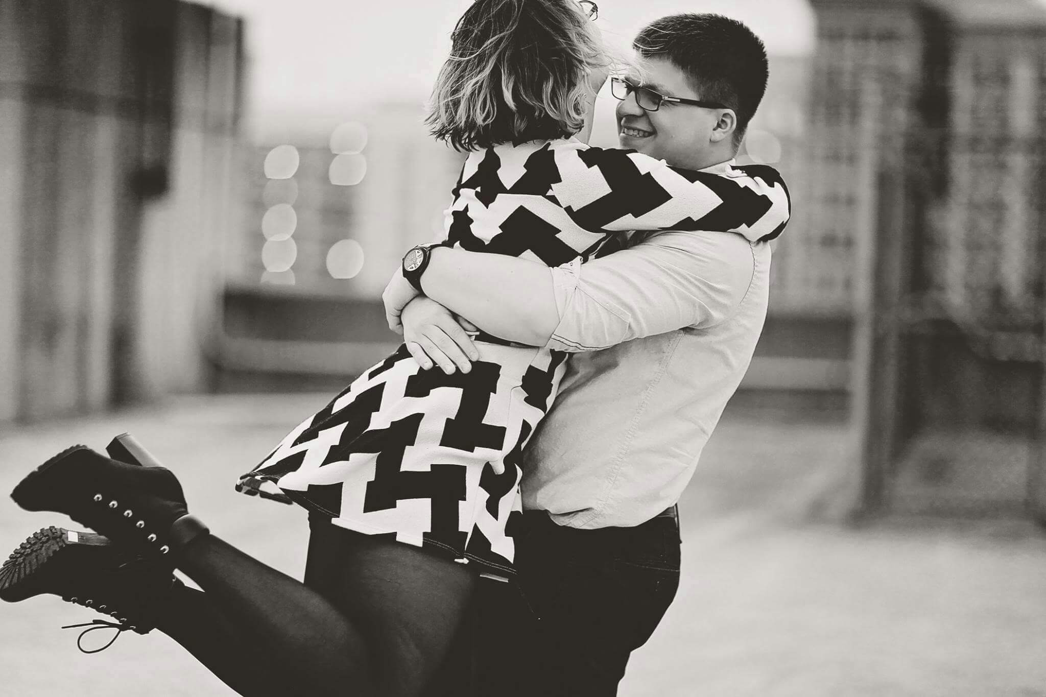 Happy couple embracing outdoors in a lively urban setting, wearing stylish outfits.