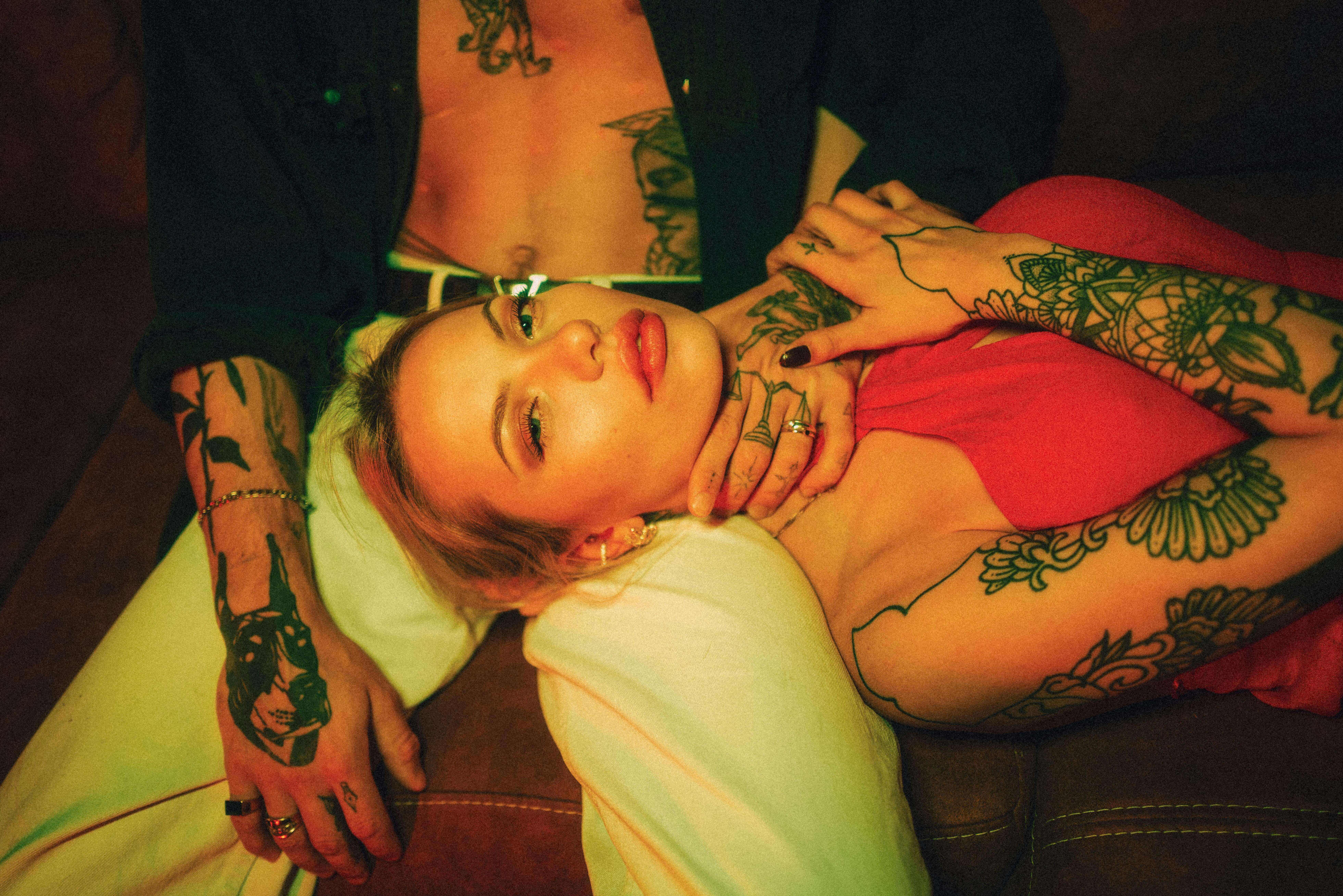 A romantic scene featuring a tattooed couple in an intimate indoor setting with warm lighting.