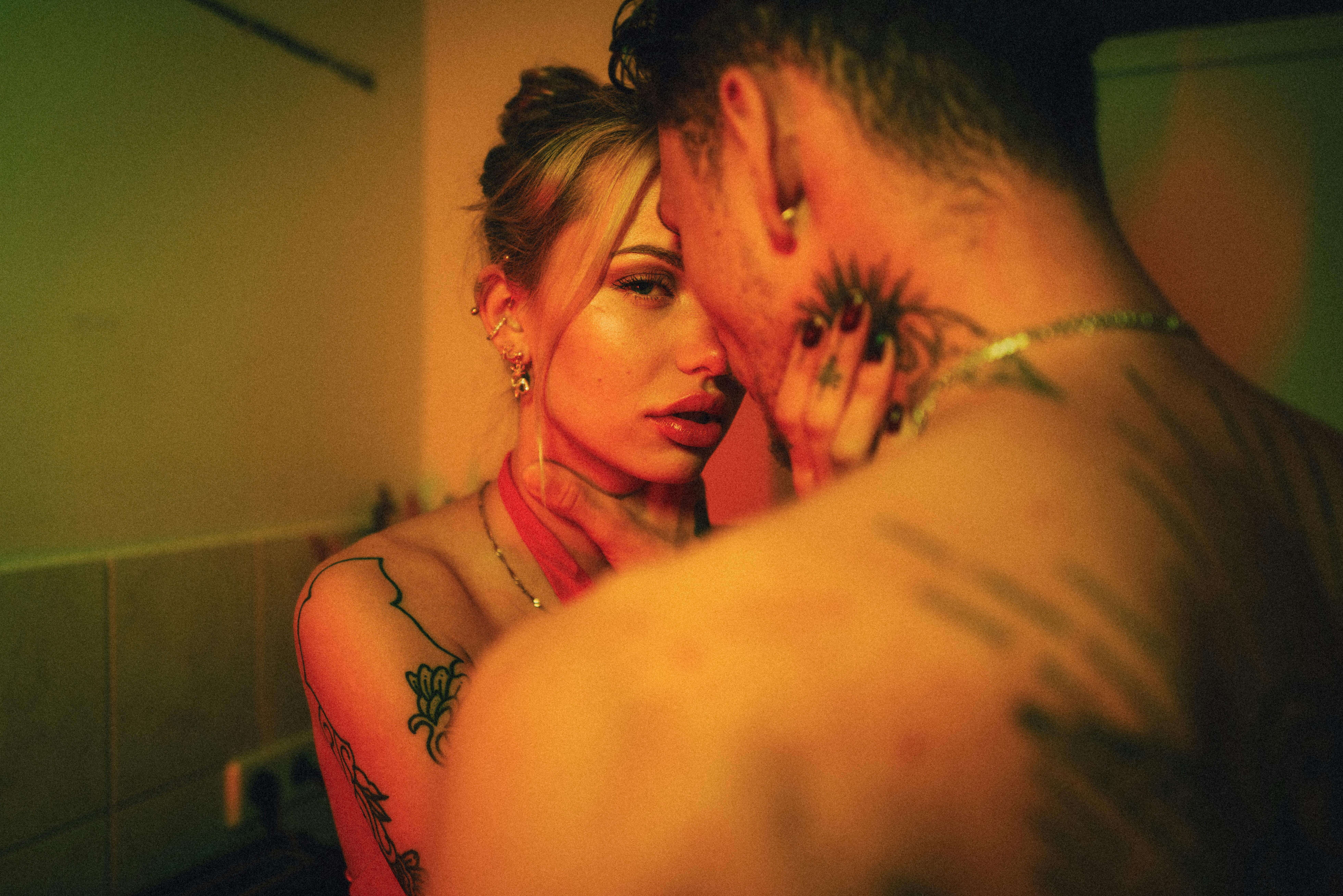 A close, intimate moment between a tattooed couple, captured in warm lighting.