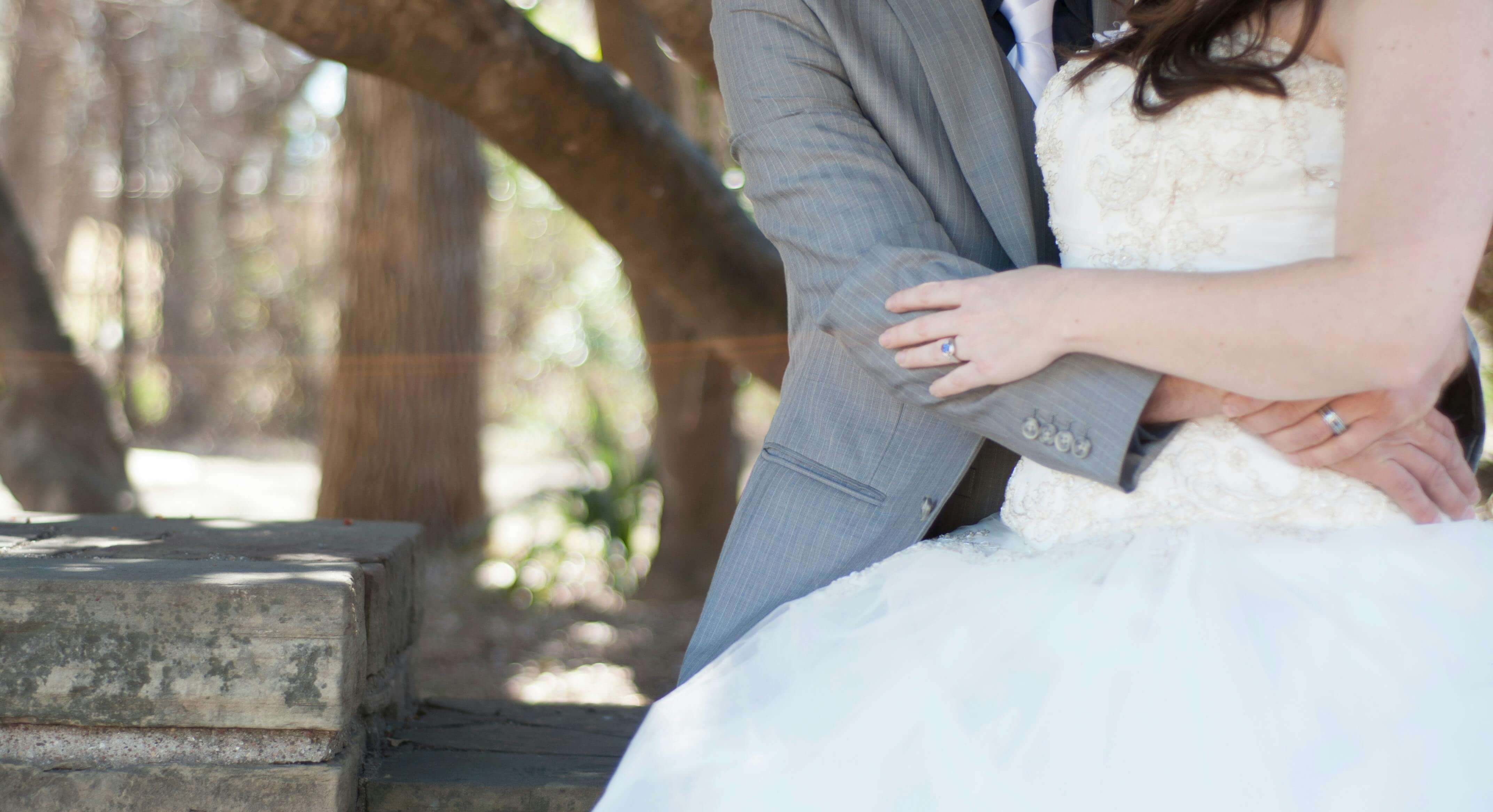 A close-up of a couple embracing on their wedding day in an outdoor setting.