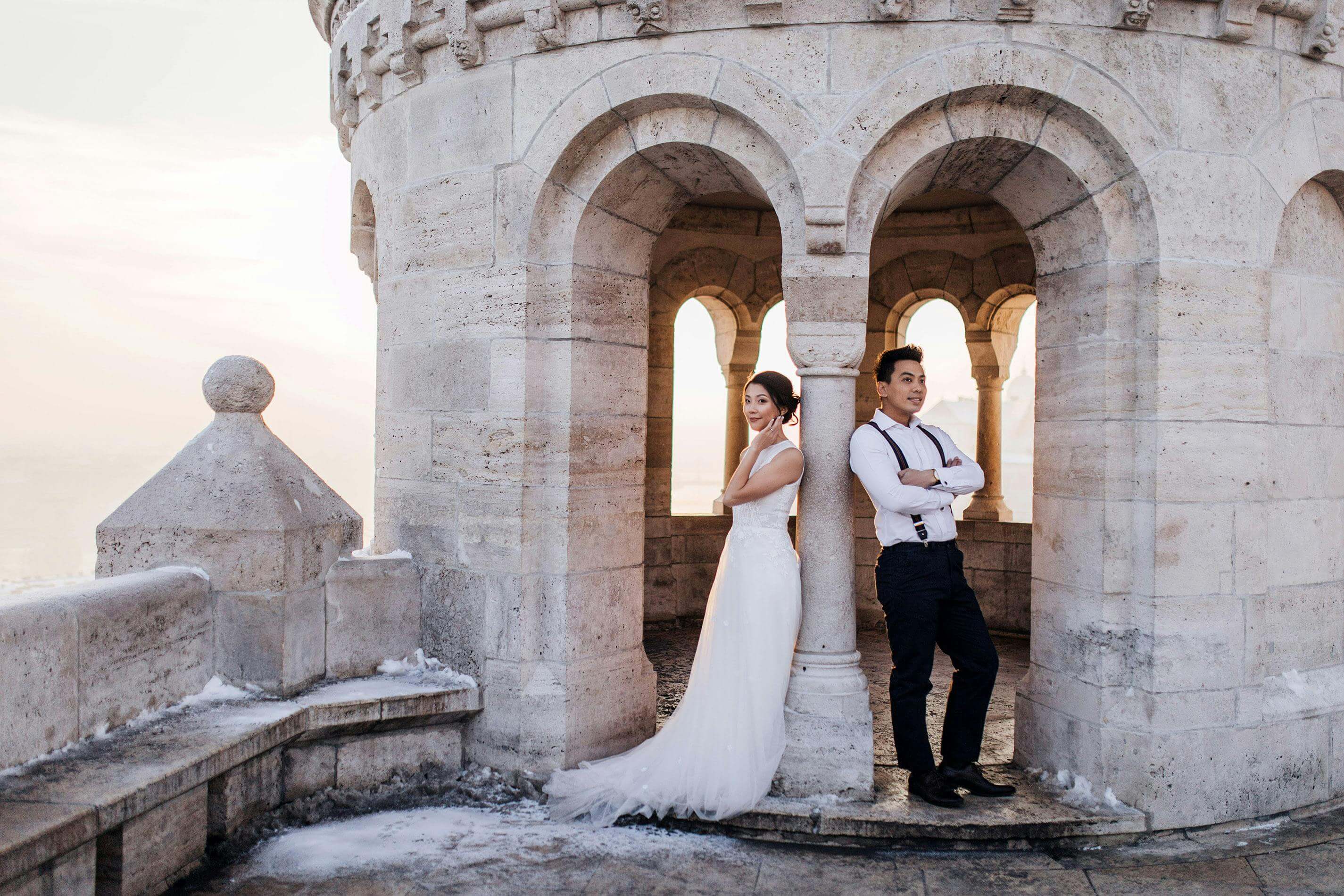 Couple posing for their wedding photoshoot at a historic castle with arches.