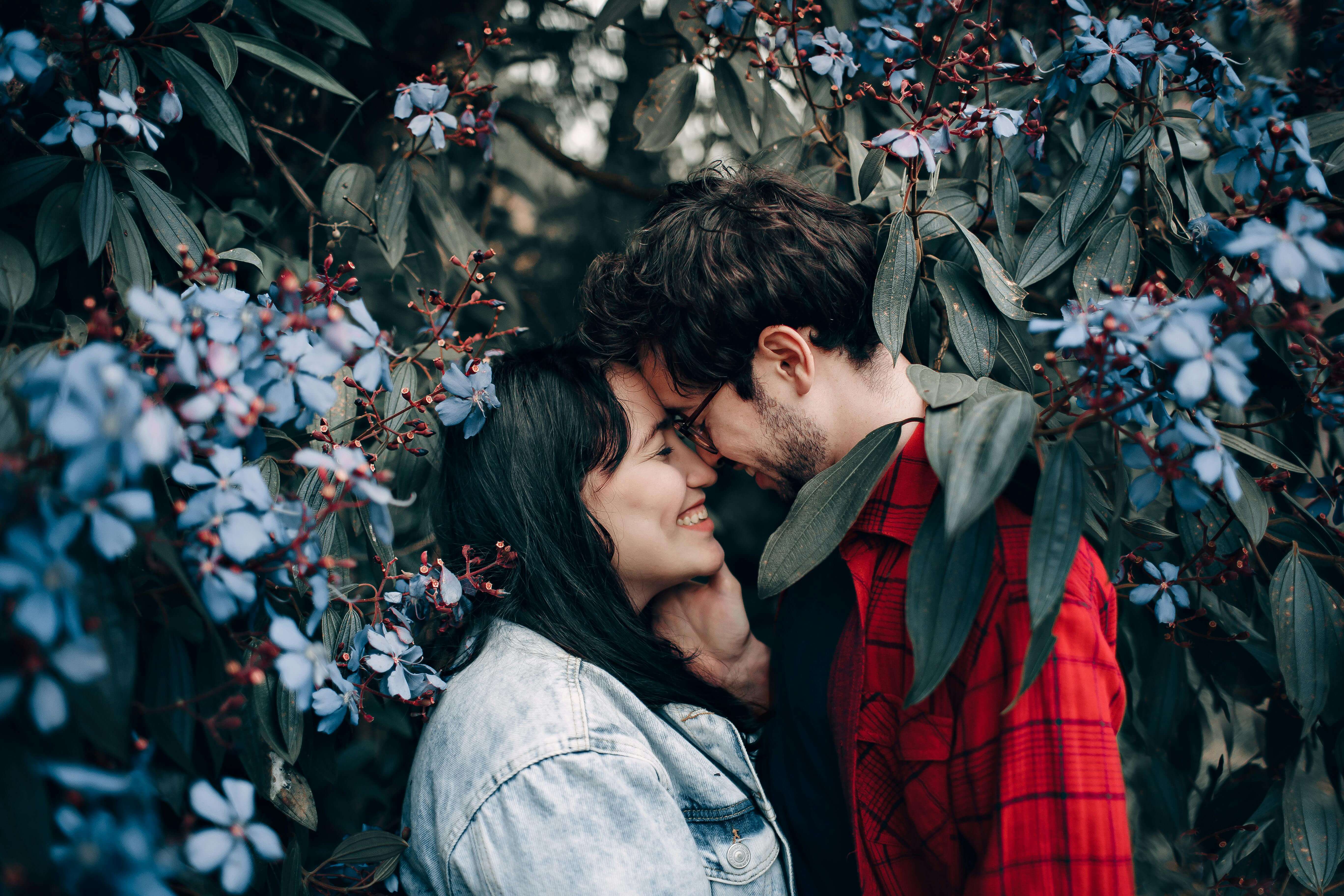 Happy couple sharing a romantic moment surrounded by beautiful blue flowers.