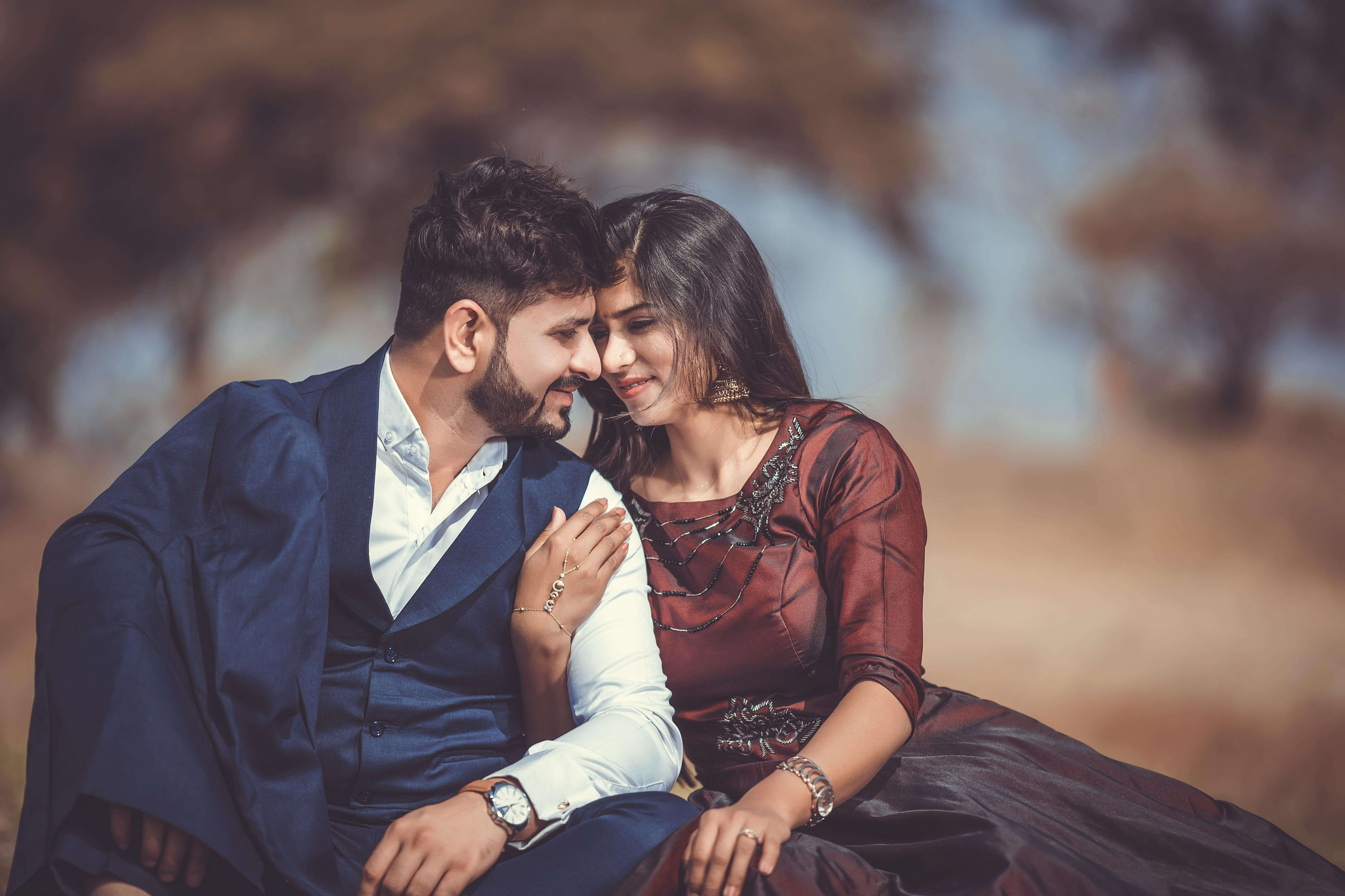 A loving couple sharing a tender moment outdoors, highlighting their romantic connection and stylish attire.