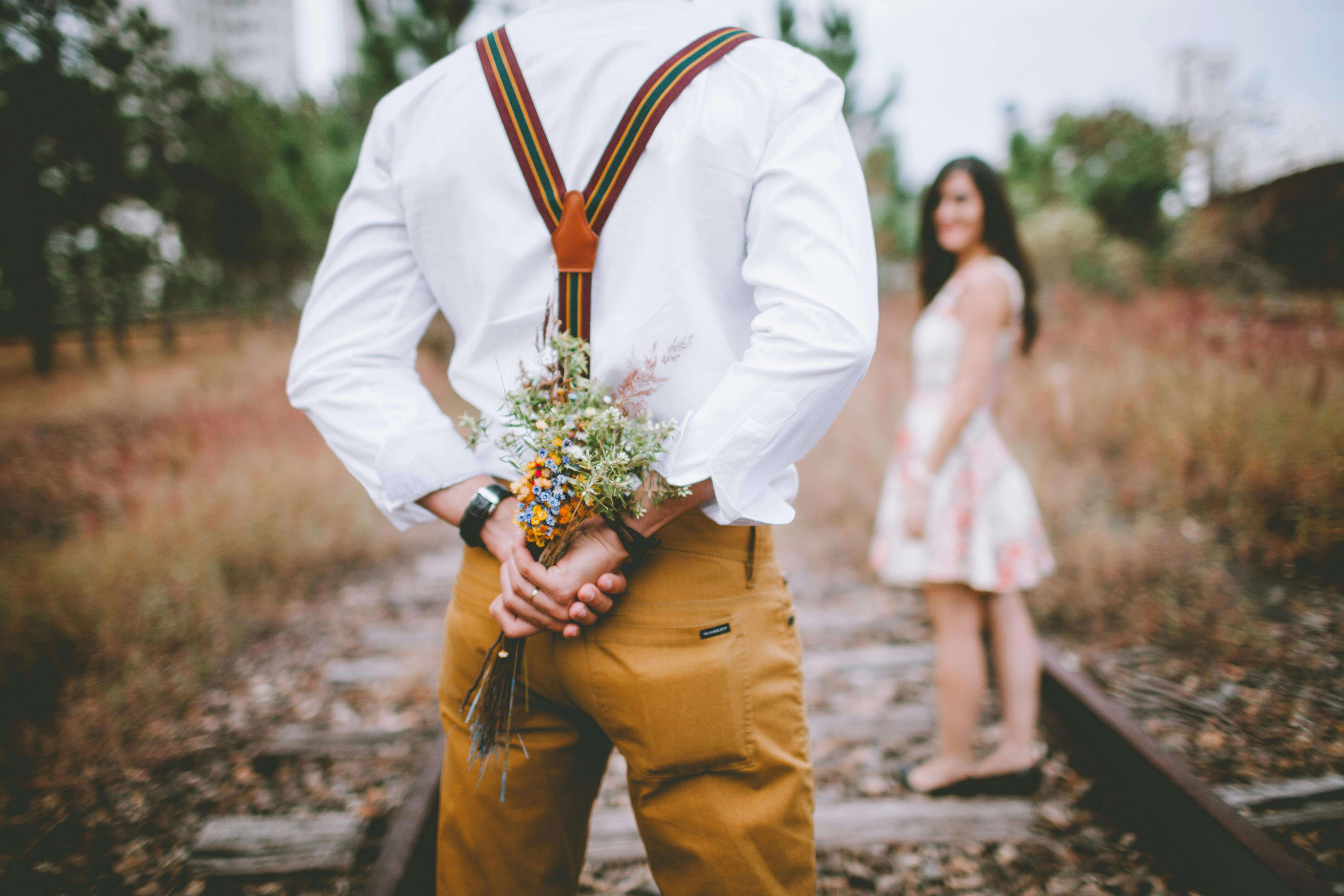 A romantic surprise proposal with a bouquet on an abandoned railway track.