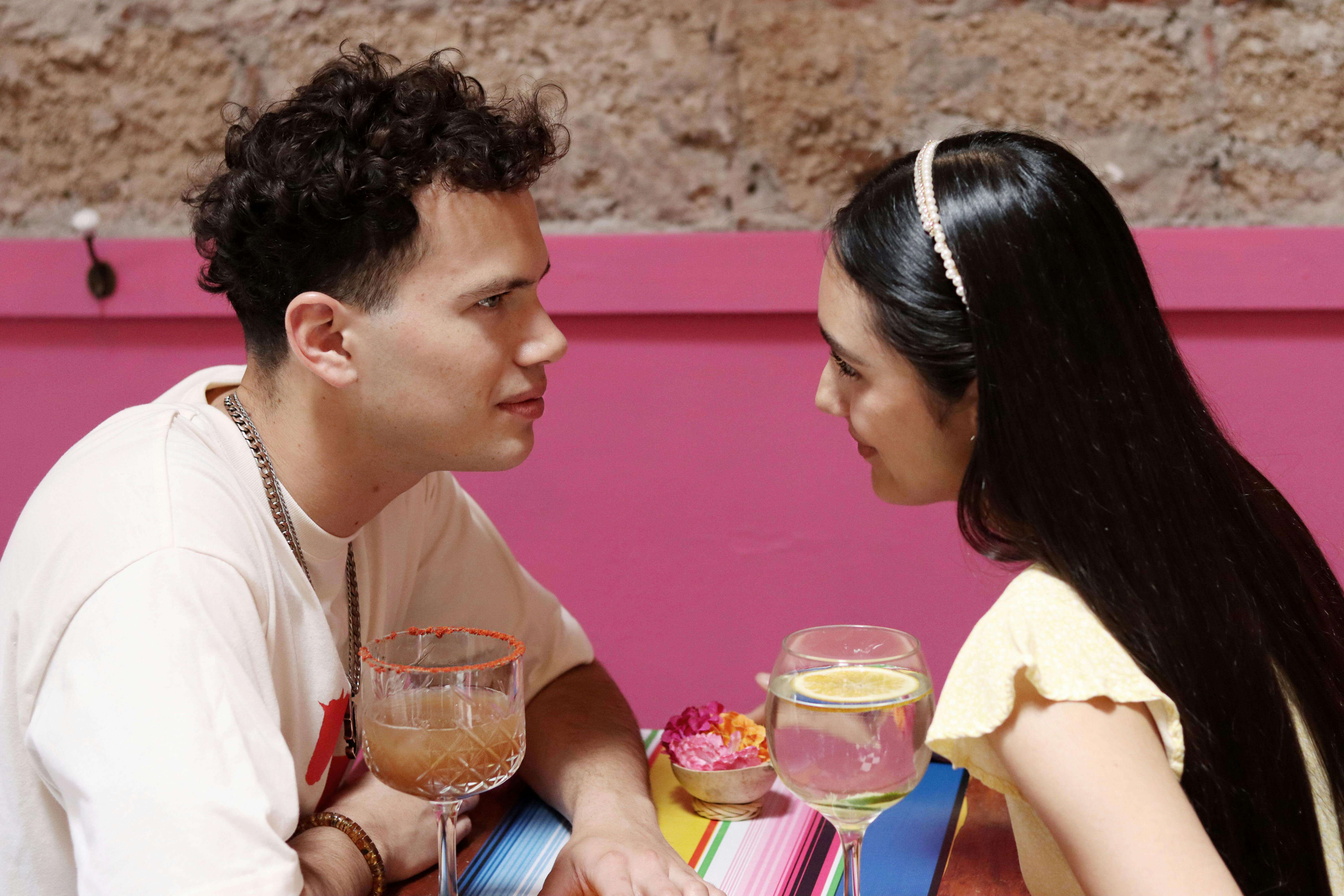 A young couple shares a moment over drinks at a vibrant cafe setting.