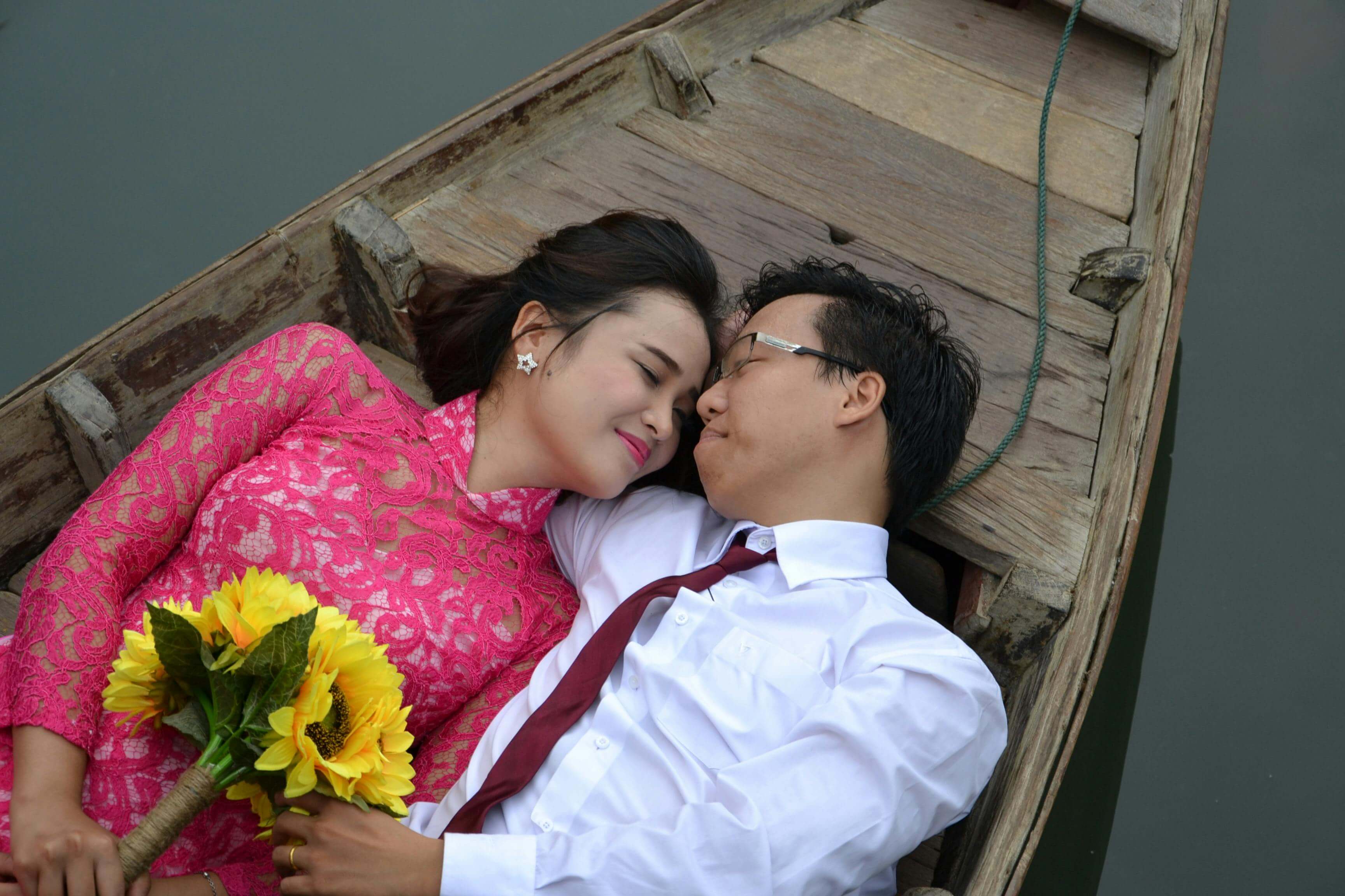 Romantic couple in traditional attire embracing on a boat, celebrating love and togetherness.