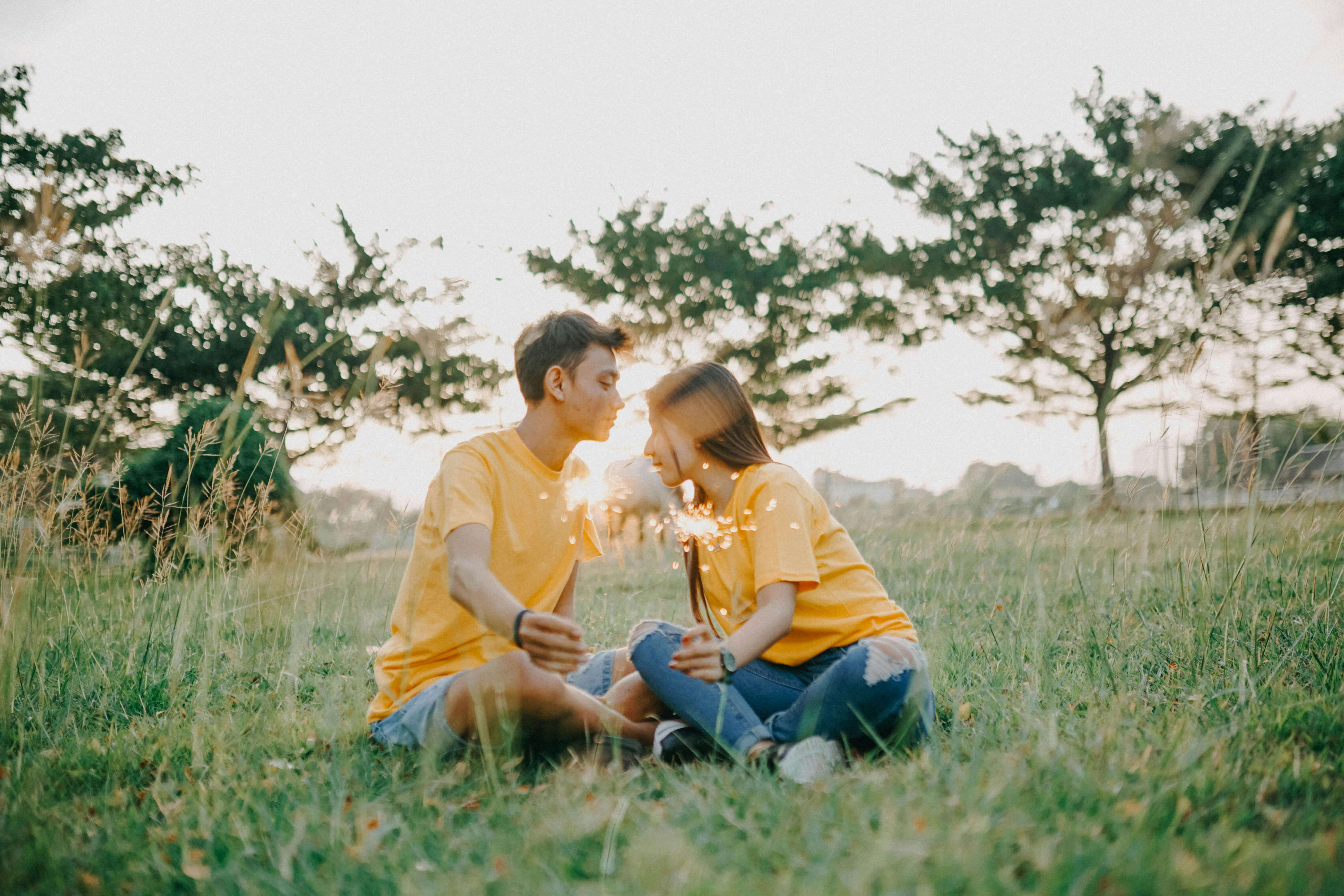 A couple holding sparklers in a serene summer field, symbolizing love and togetherness.