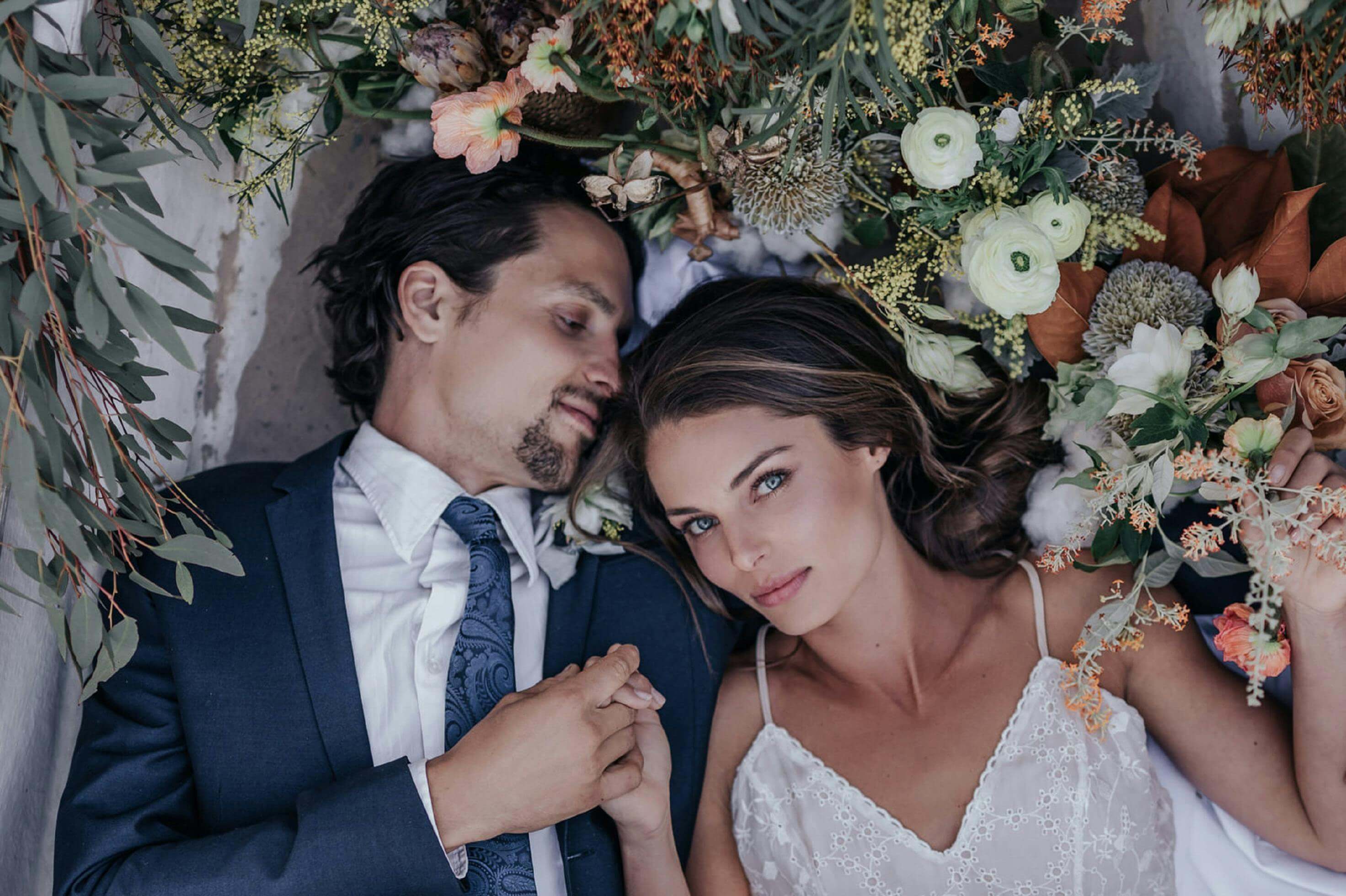 Intimate portrait of a loving bride and groom surrounded by flowers, capturing their romantic wedding day.