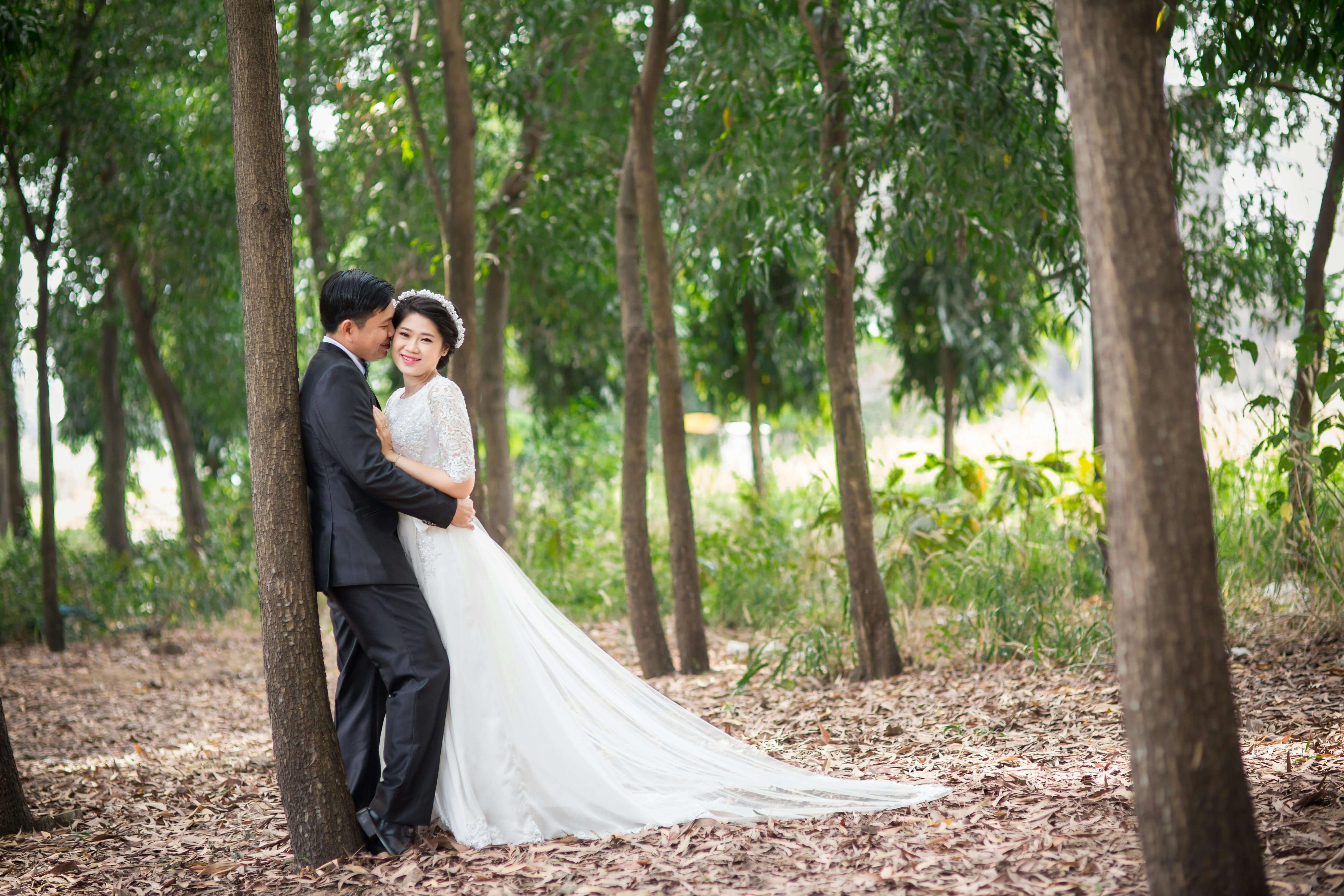 Bride and groom share tender moment in a serene forest setting.