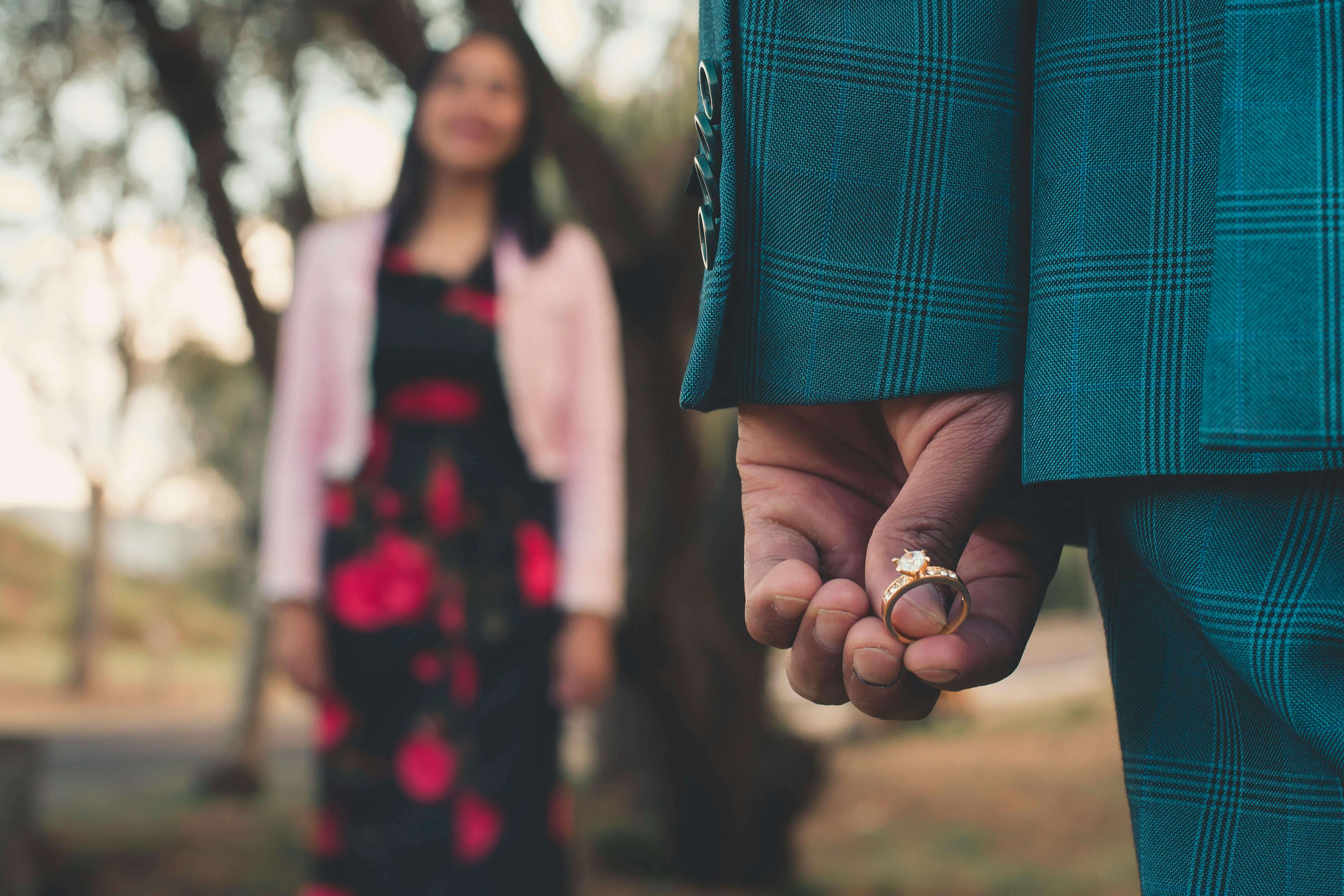 A romantic outdoor engagement scene with a diamond ring and couple in love.