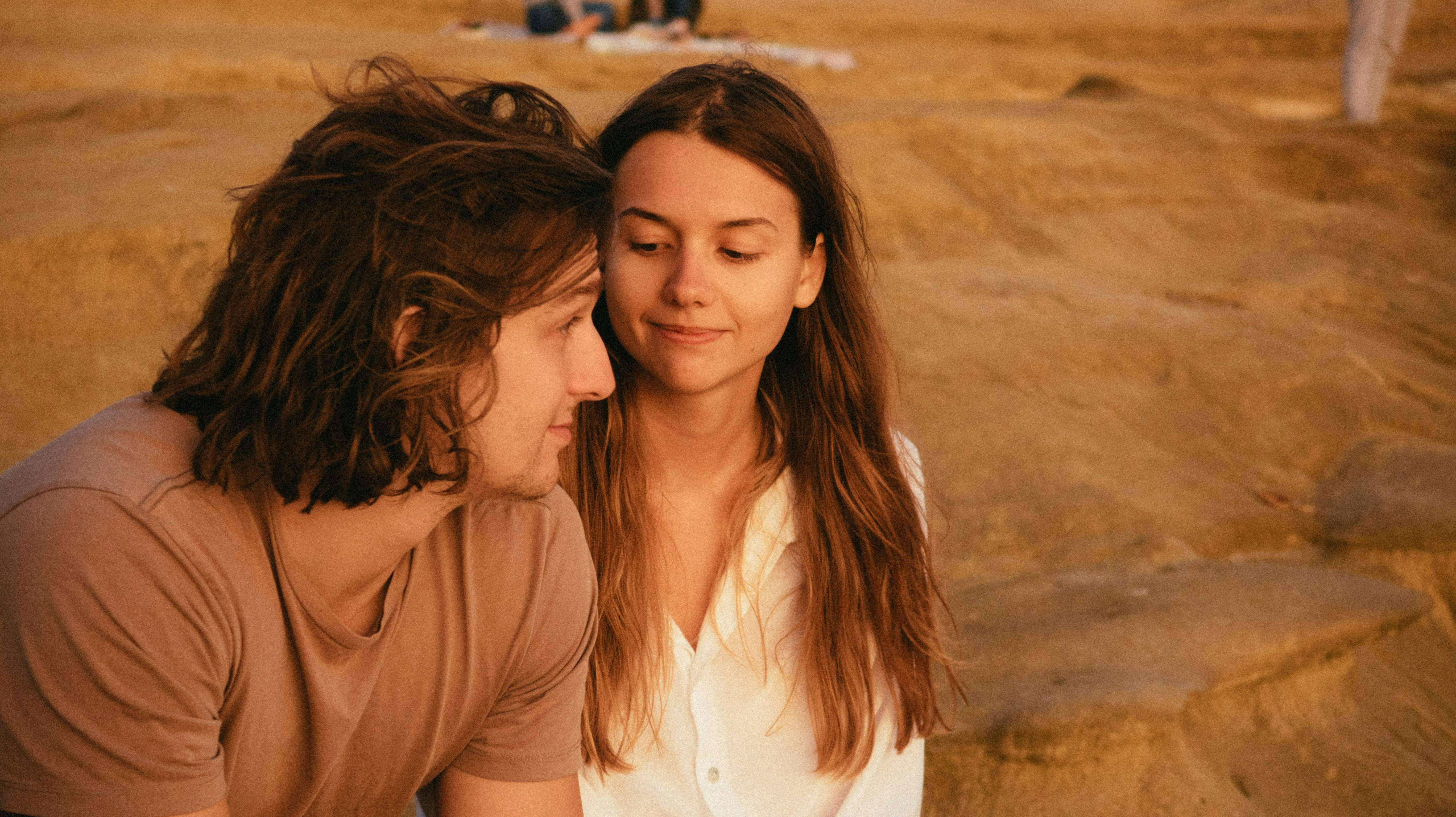 A couple enjoying a serene moment together by a sandy landscape during the day.