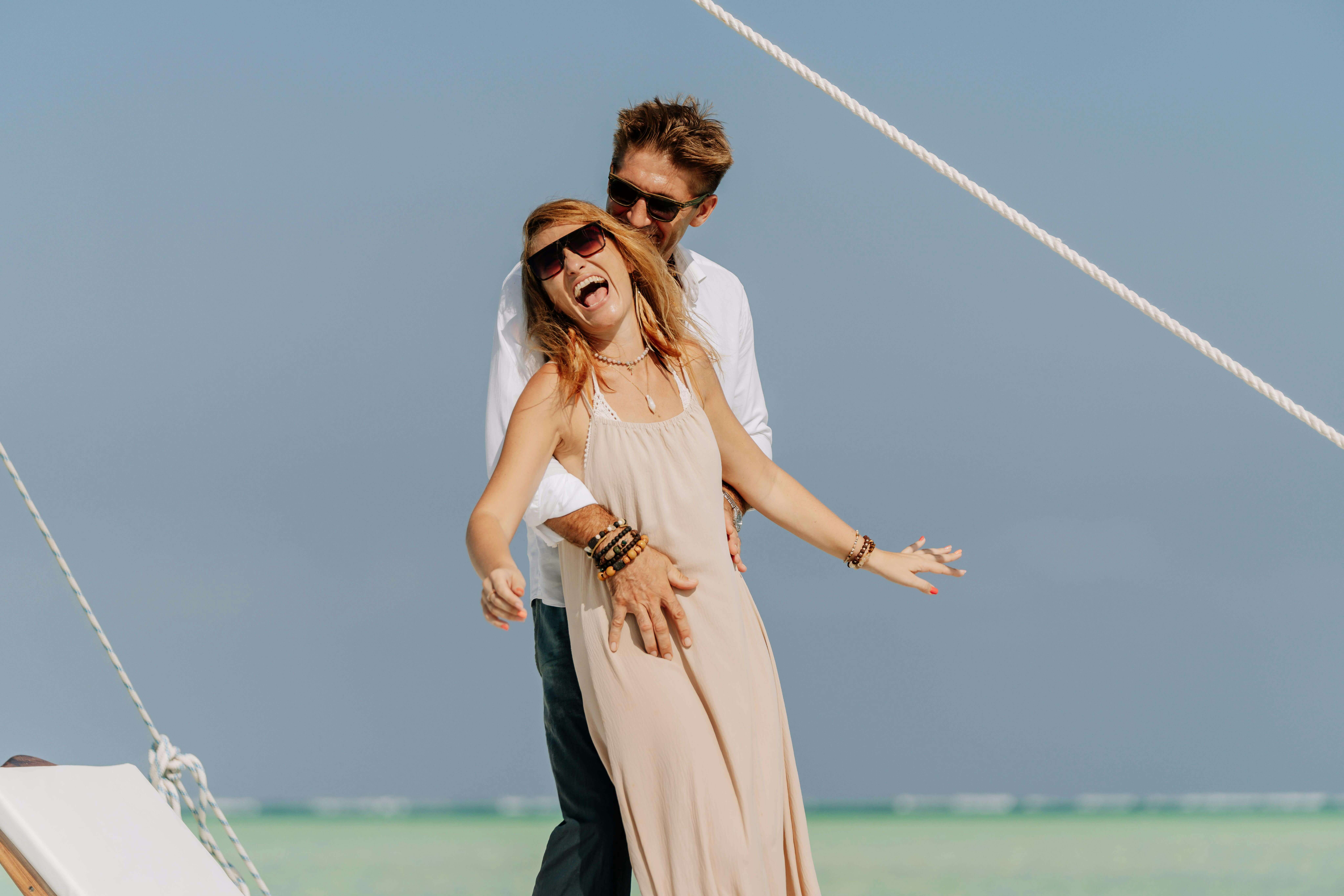 A happy couple laughs together on a yacht in Zanzibar, embodying a carefree vacation vibe.