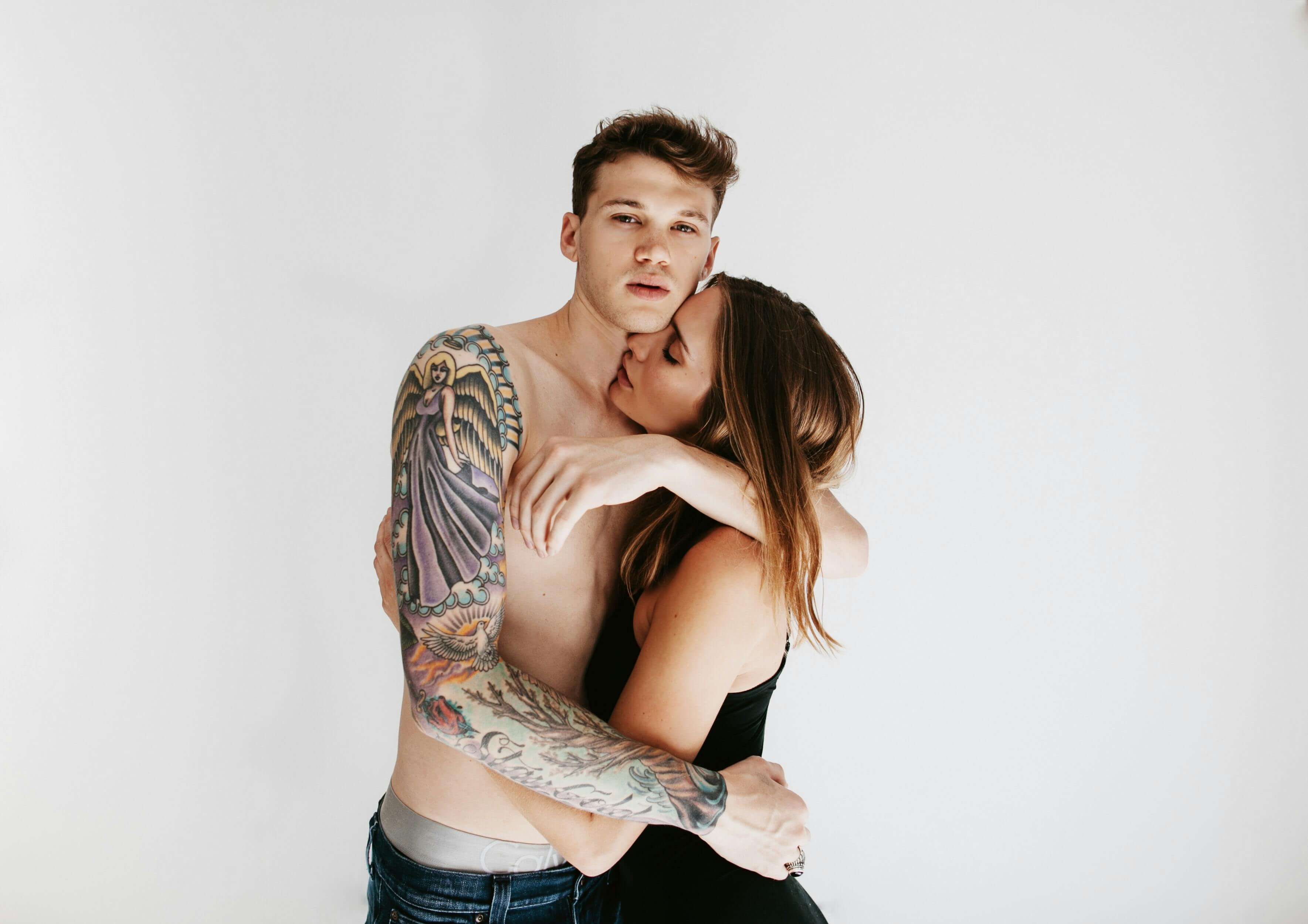 Intimate portrait of a tattooed man and a woman embracing lovingly, showcasing modern romance.