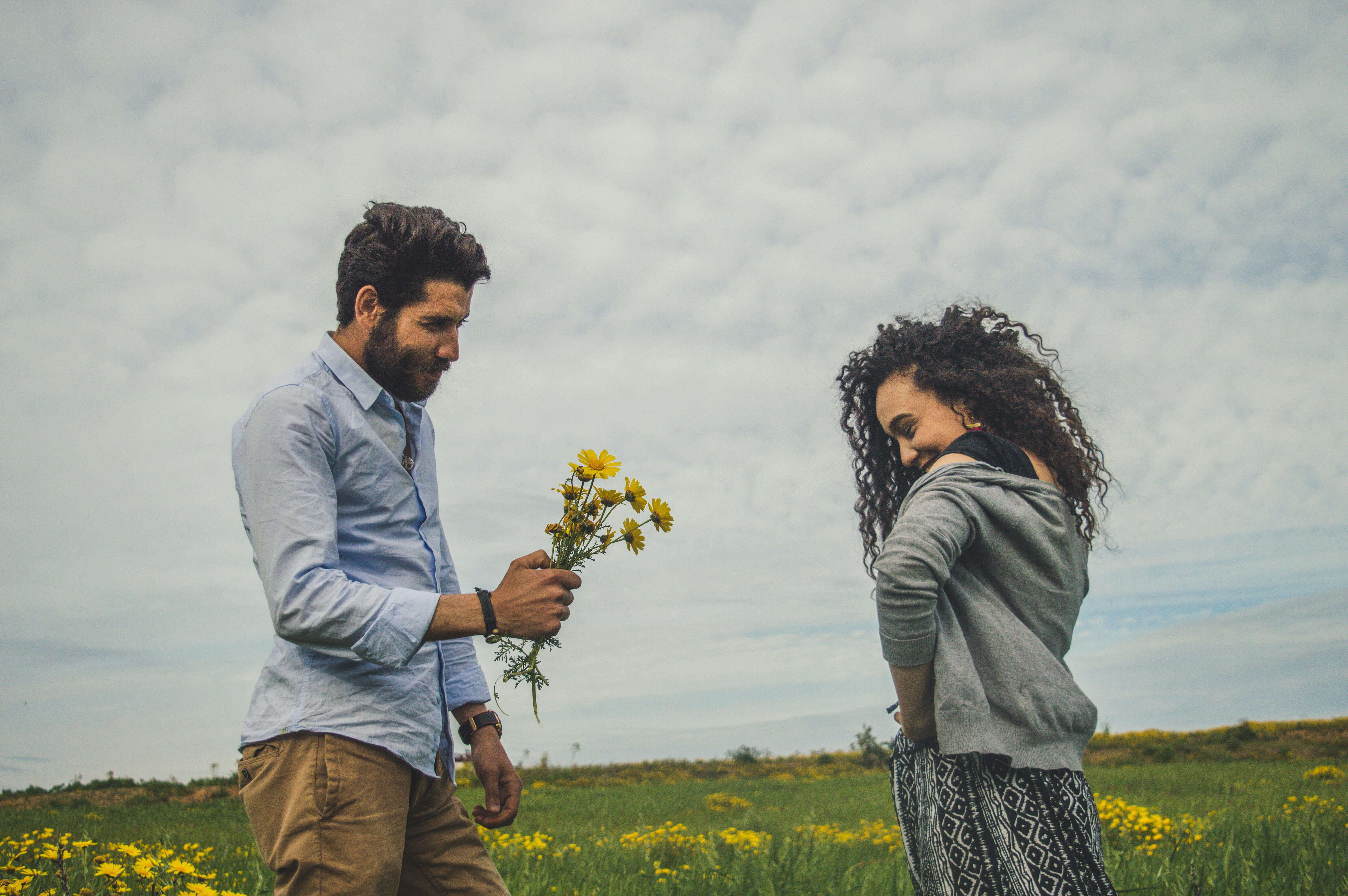 A young couple shares a romantic moment in a field with yellow flowers.