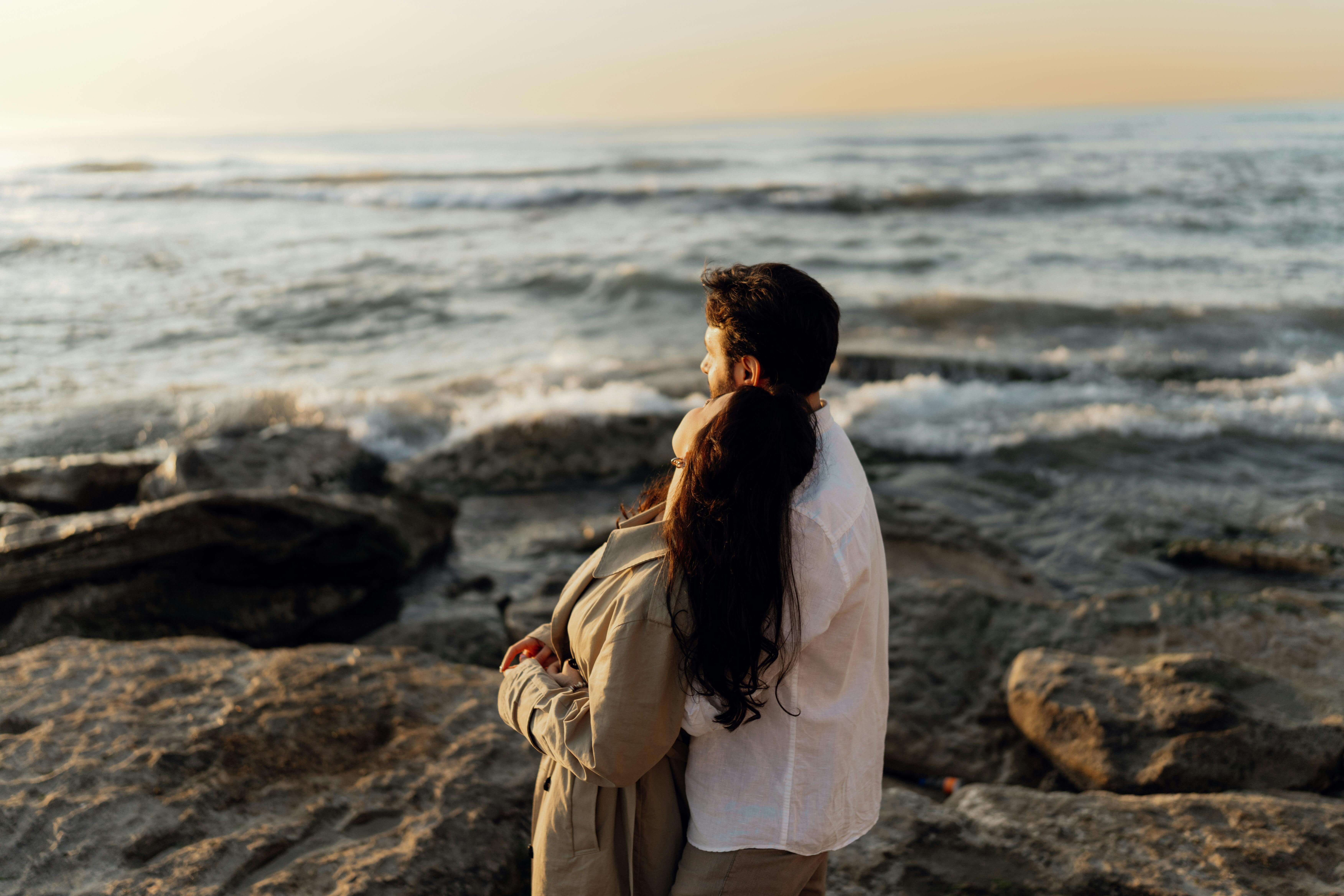 A couple enjoying a romantic moment by the ocean at sunset, offering a sense of tranquility and connection.