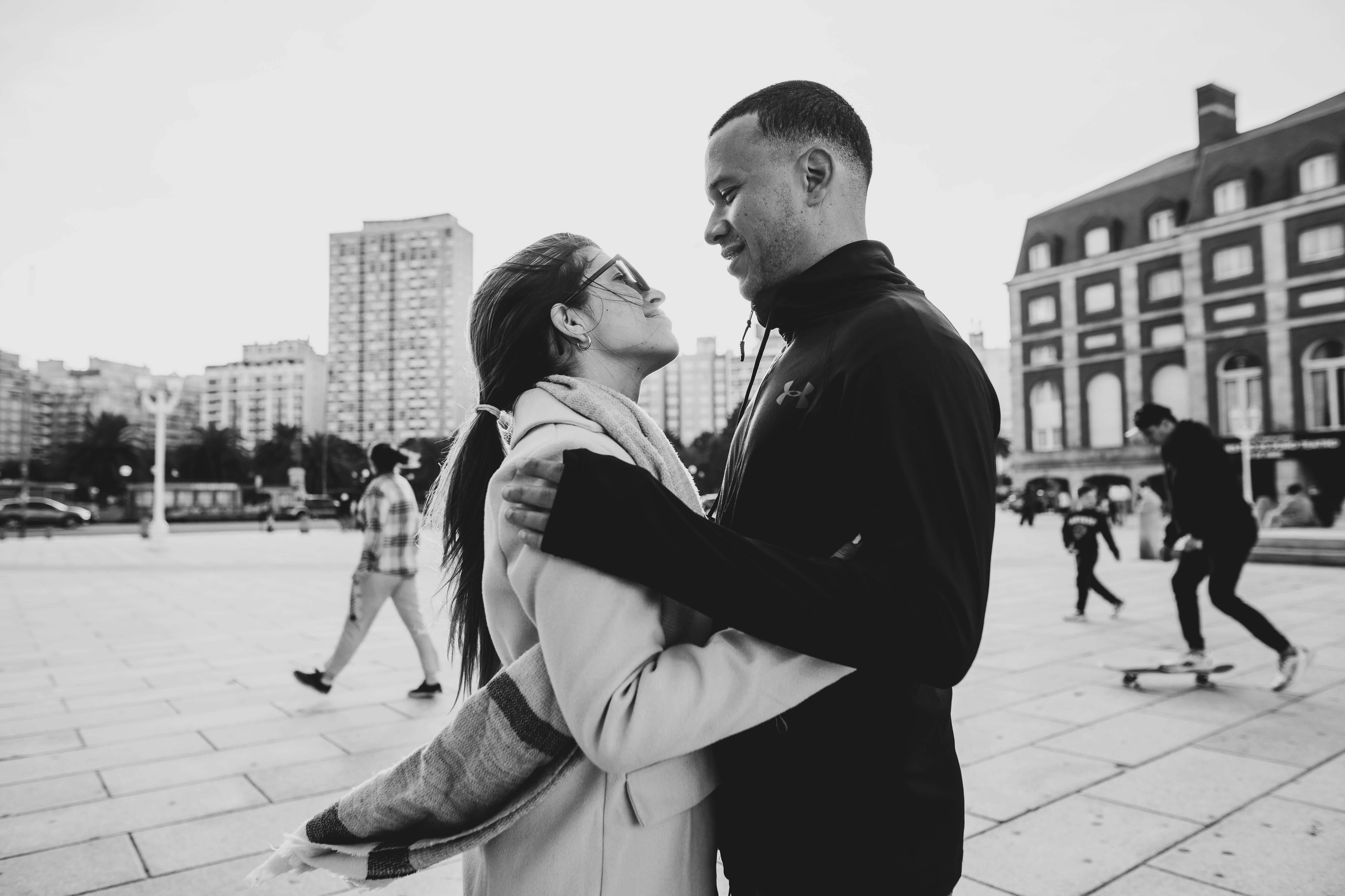 A romantic black and white photo of a couple embracing in a bustling urban landscape.