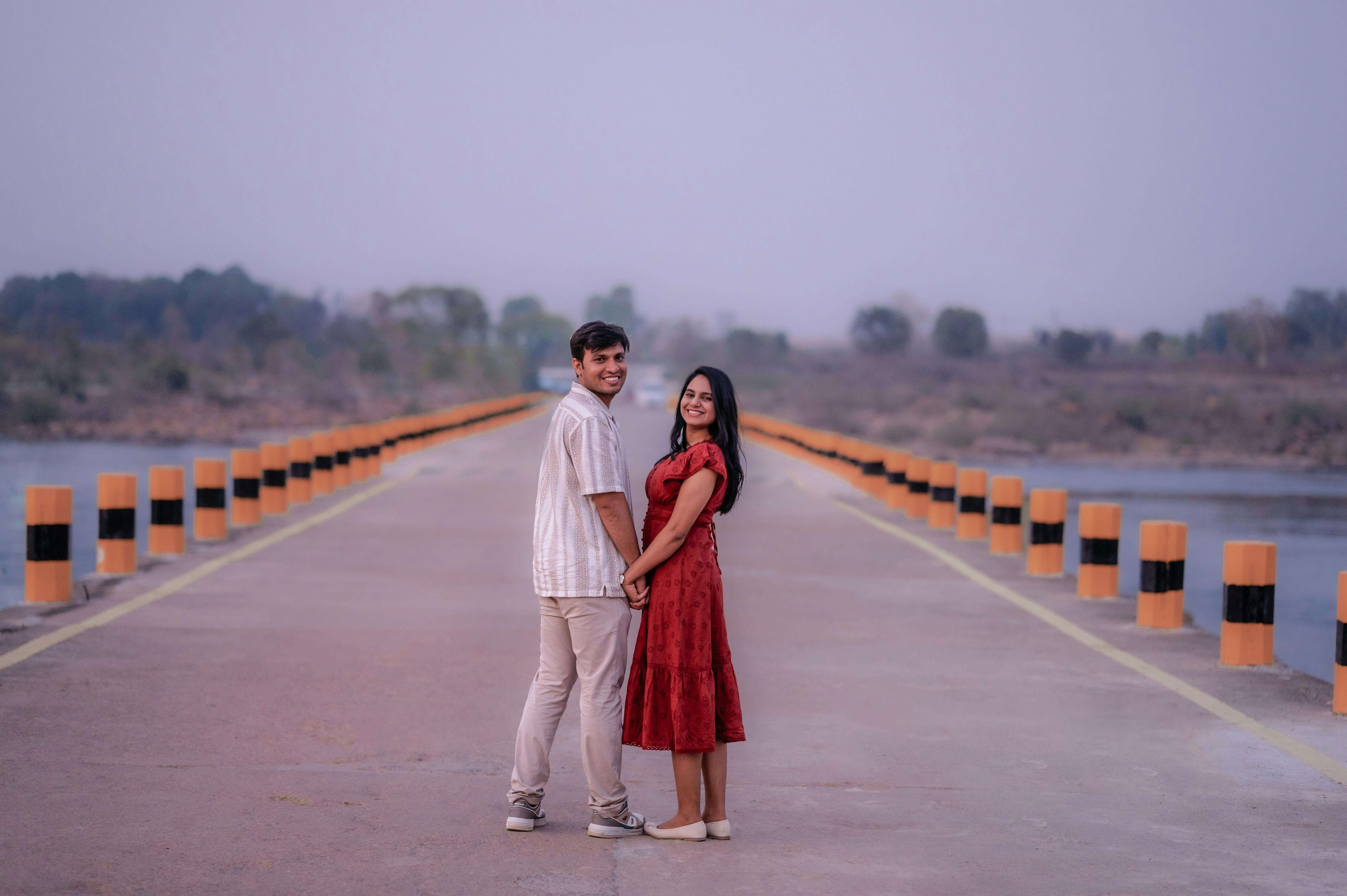 A romantic couple on a scenic bridge, holding hands and embracing peaceful love.