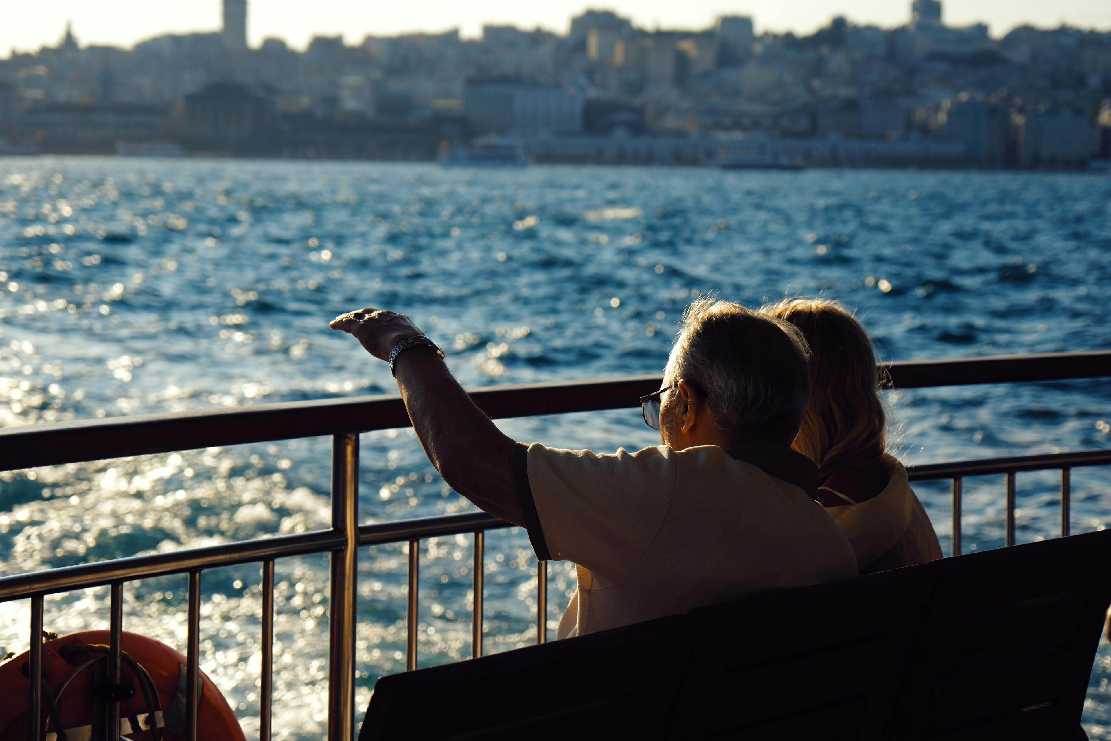 Senior couple enjoys cityscape and sea views on a ferry ride during the day.