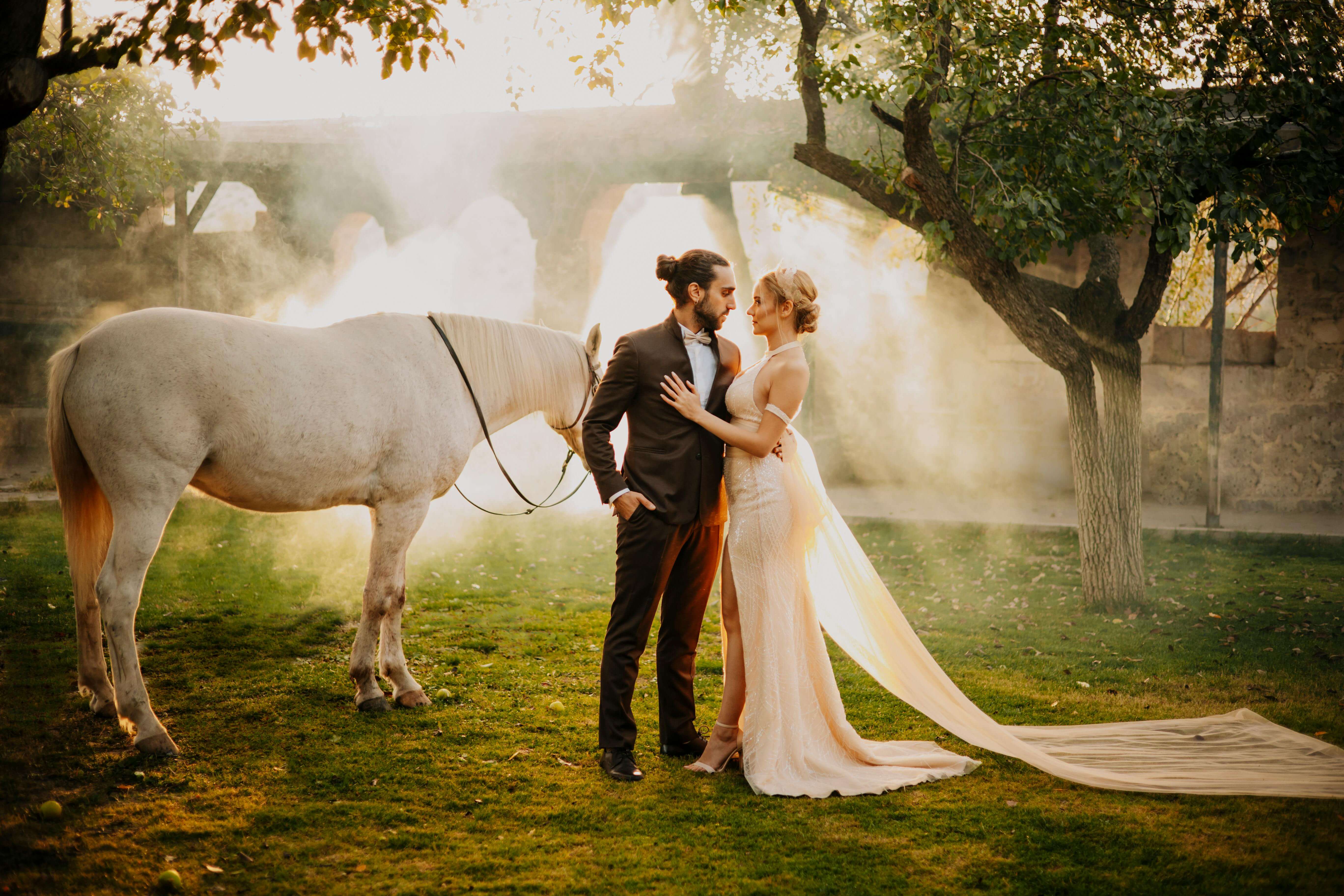 A couple shares an intimate moment at a Türkiye horse ranch, bathed in golden light.