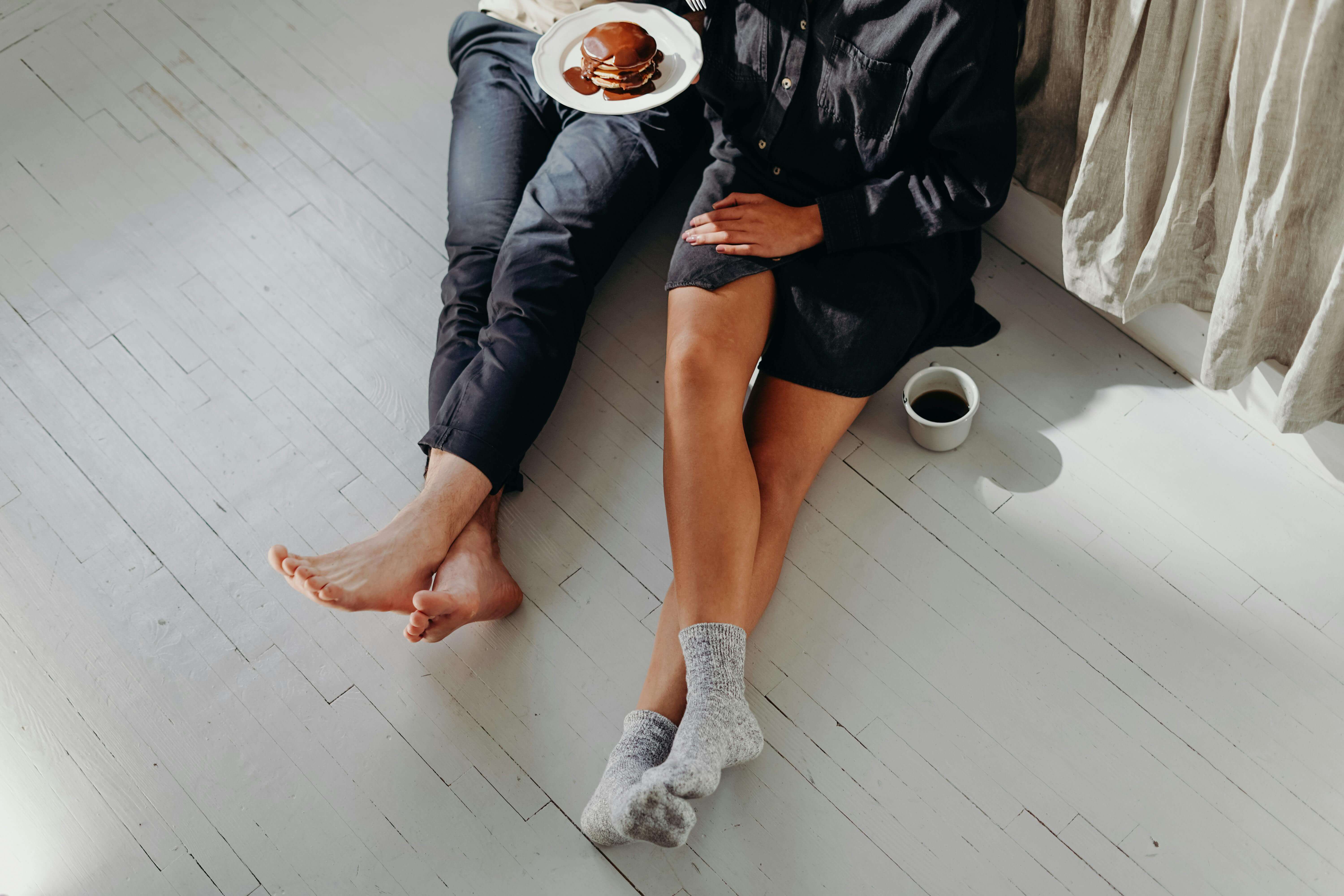 A cozy couple enjoying a quiet breakfast with pancakes and coffee on a sunlit floor.